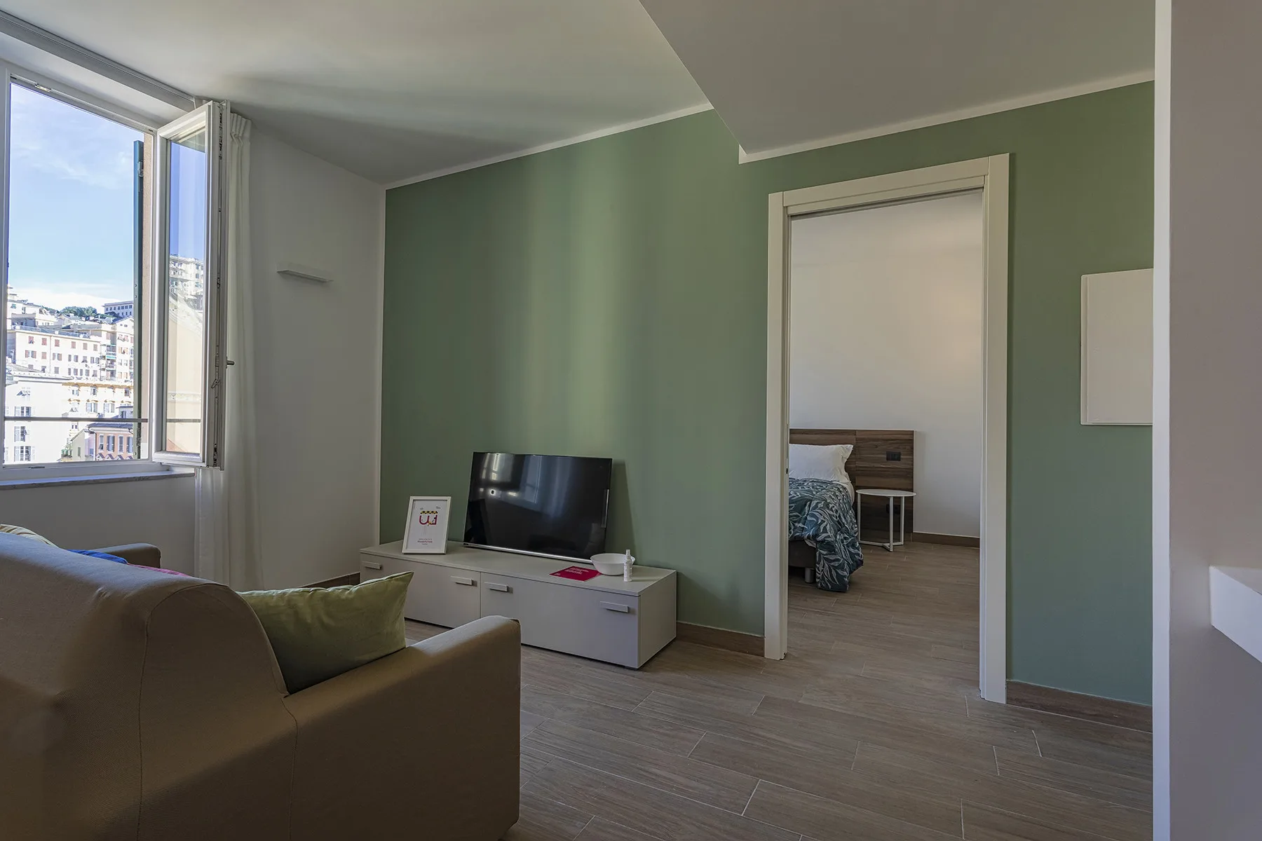 Una sala de estar con asientos y un televisor junto a una puerta abierta.