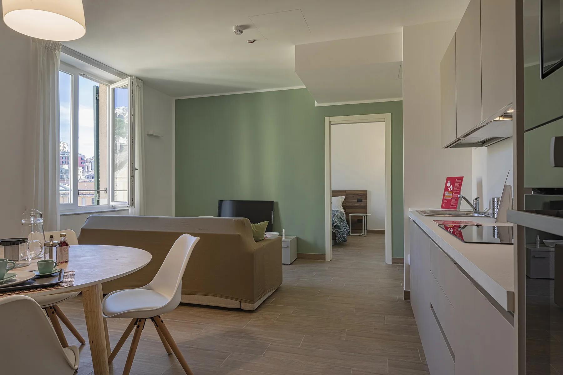 Una zona combinada de sala y cocina con mesa de comedor y ventanales.