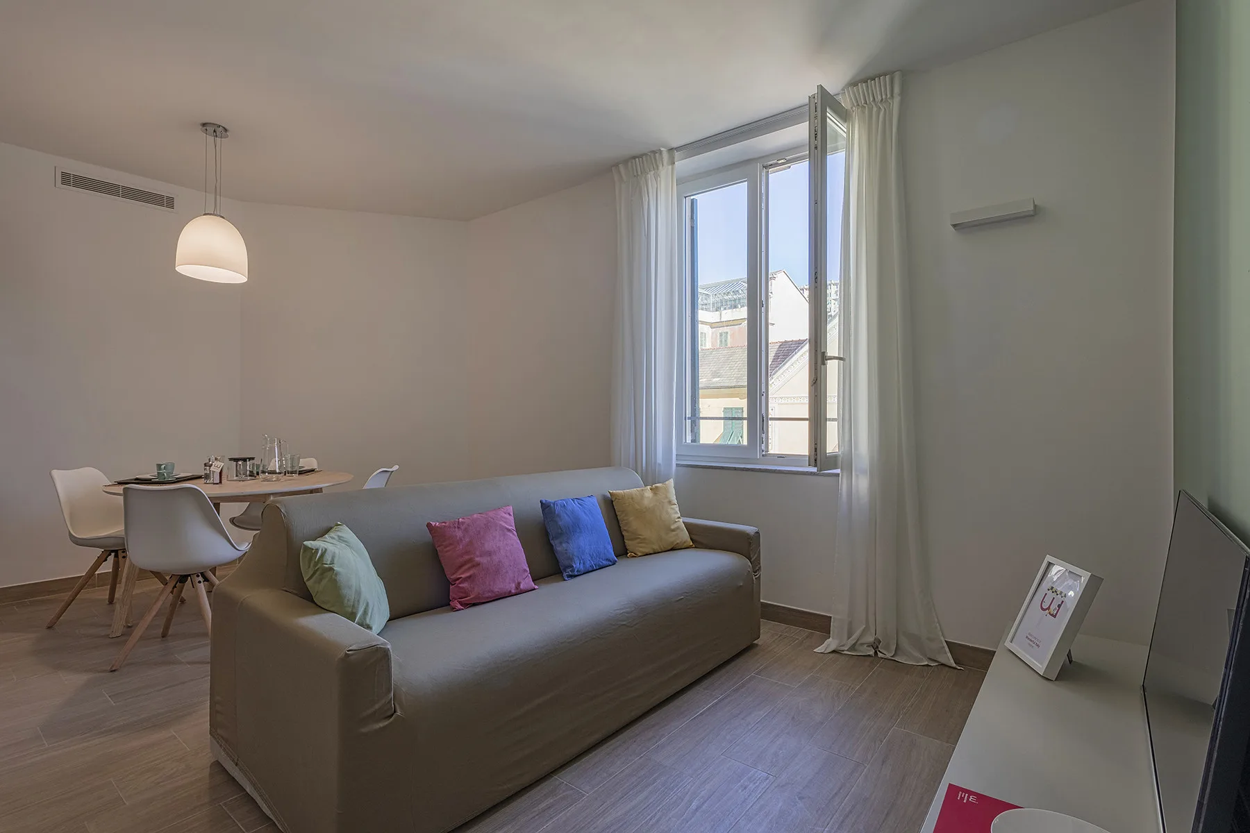 Una sala de estar con asientos, una mesa de comedor y una ventana grande.