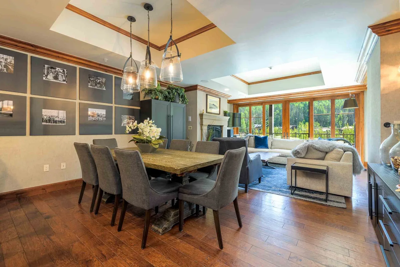 An open-plan dining and living room with a table, seating, and large windows.