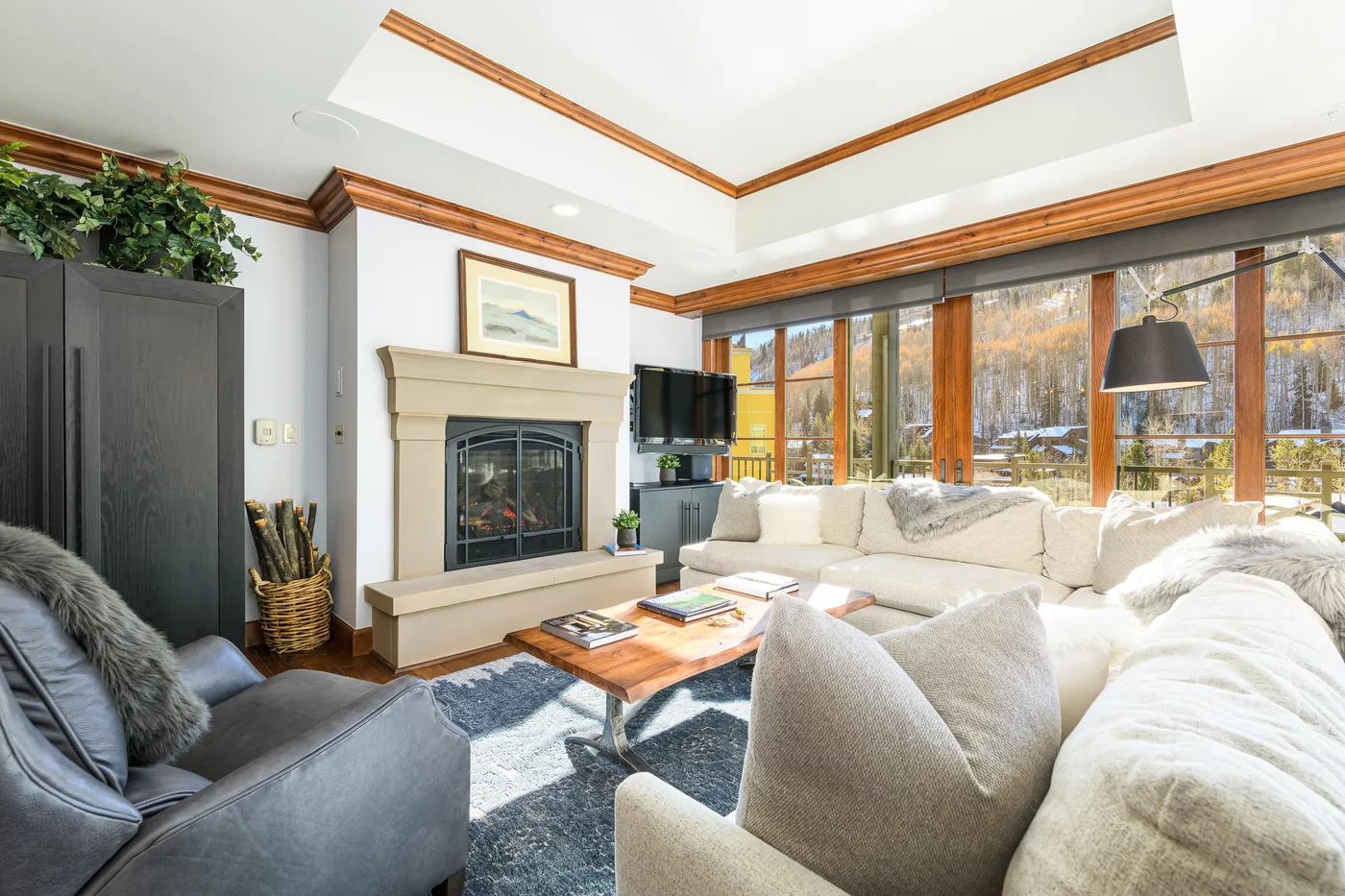 A bright living room with ample seating, a fireplace, and large windows.