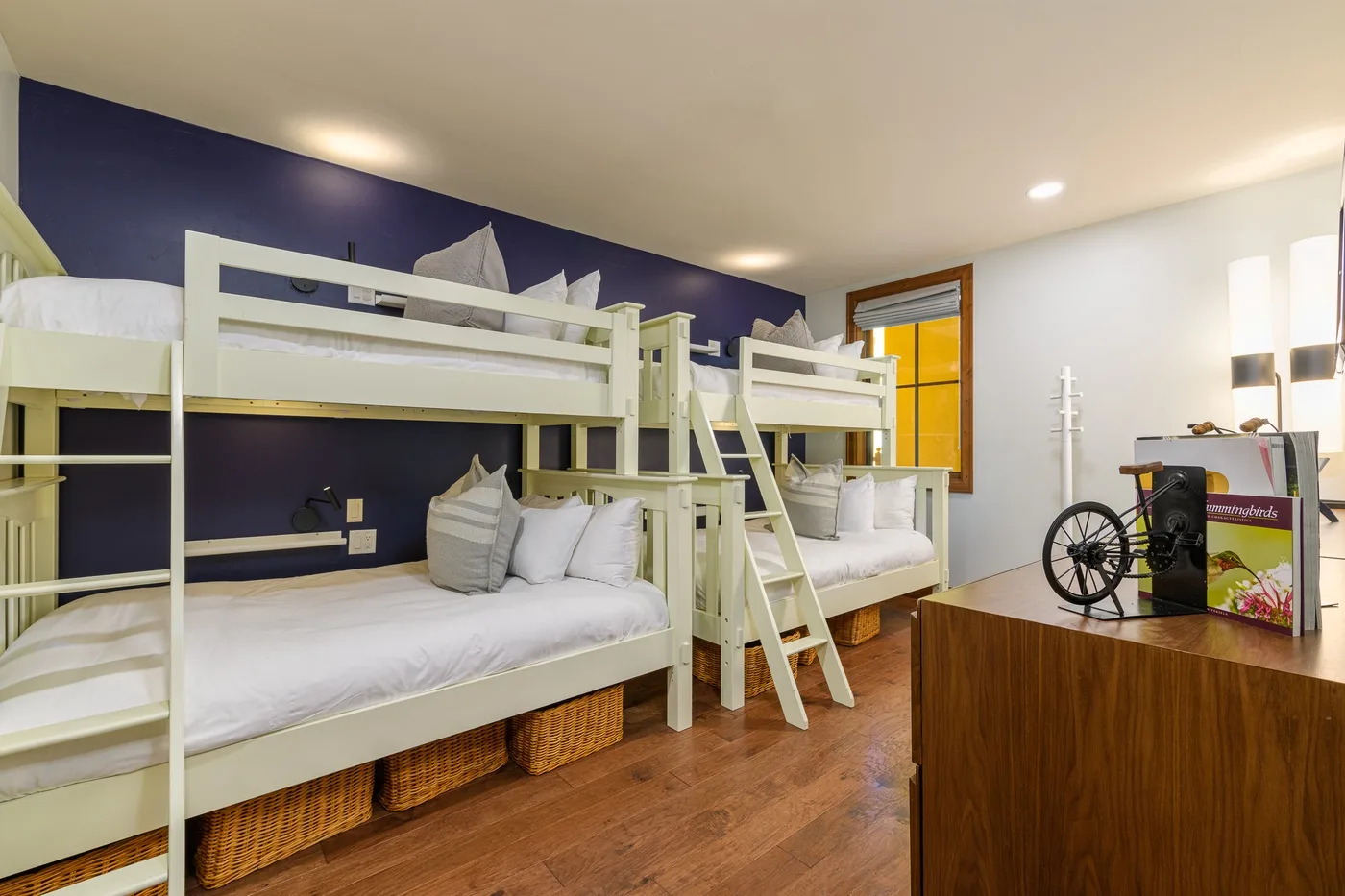 A shared sleeping area with white bunk beds and a dark blue wall.