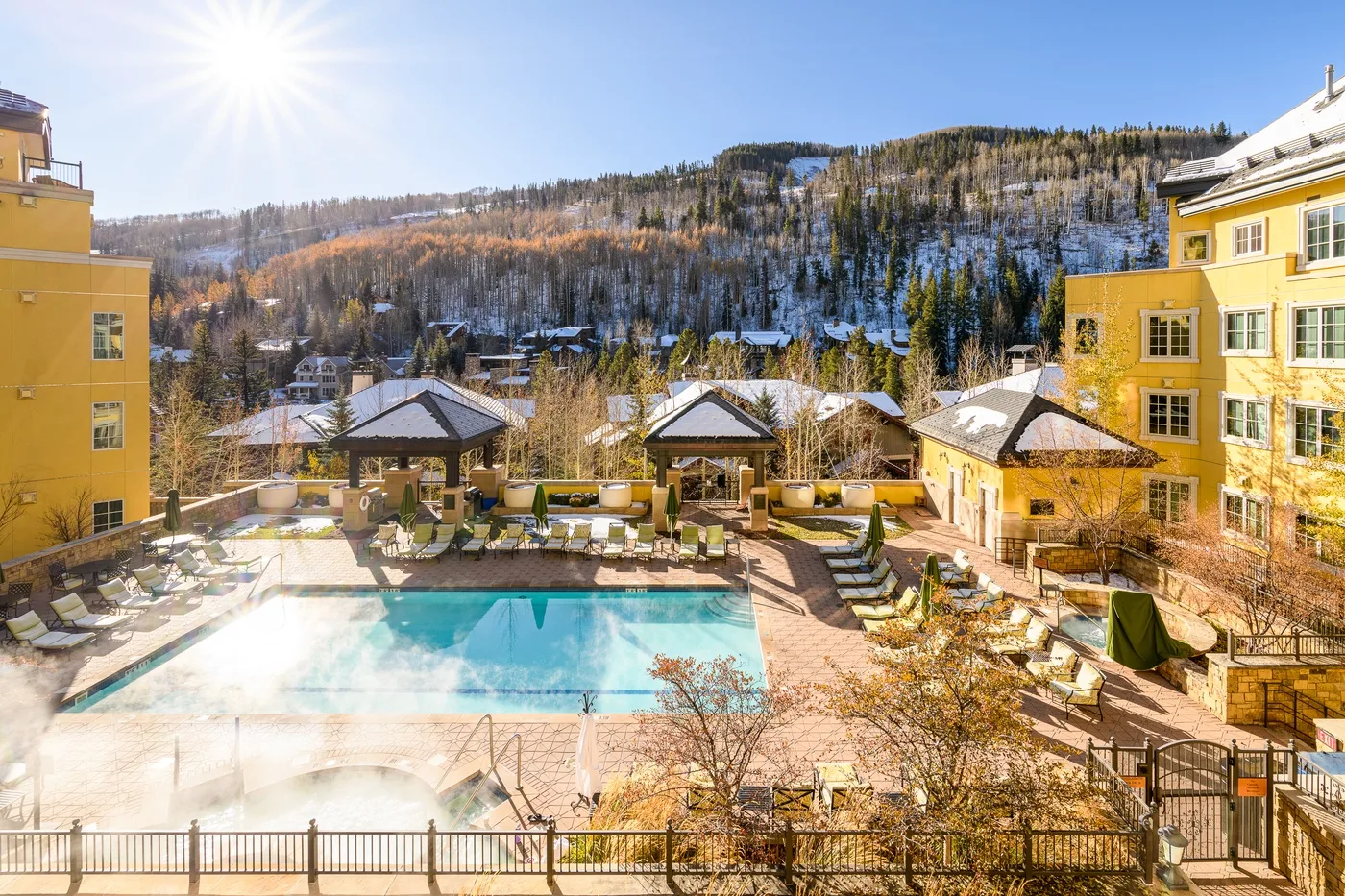 An outdoor pool and surrounding seating overlook a snow-dusted mountain landscape.