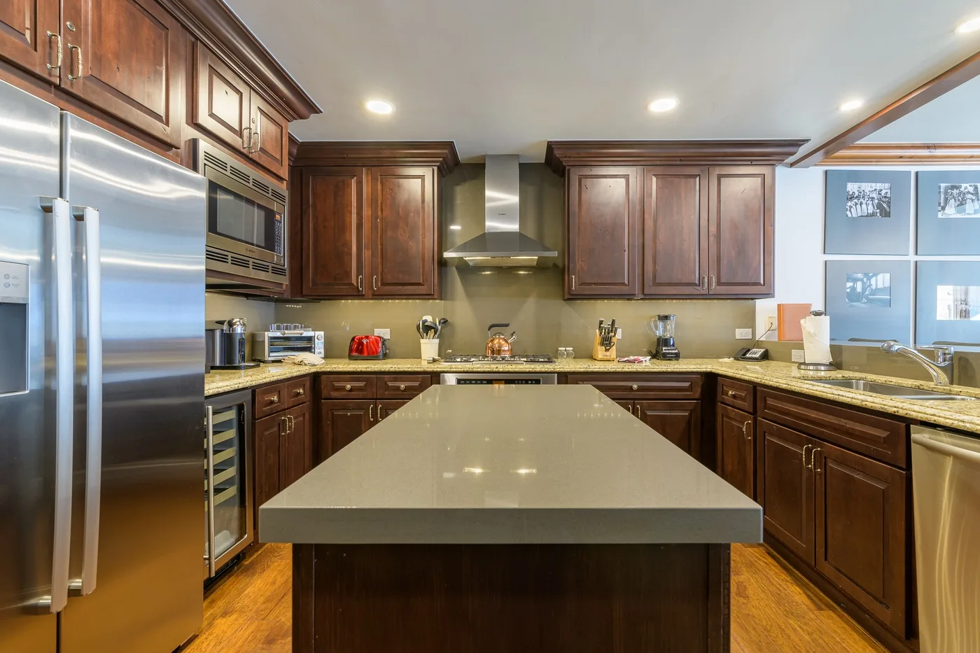 A kitchen with dark wood cabinets, stainless steel appliances, and a large island.