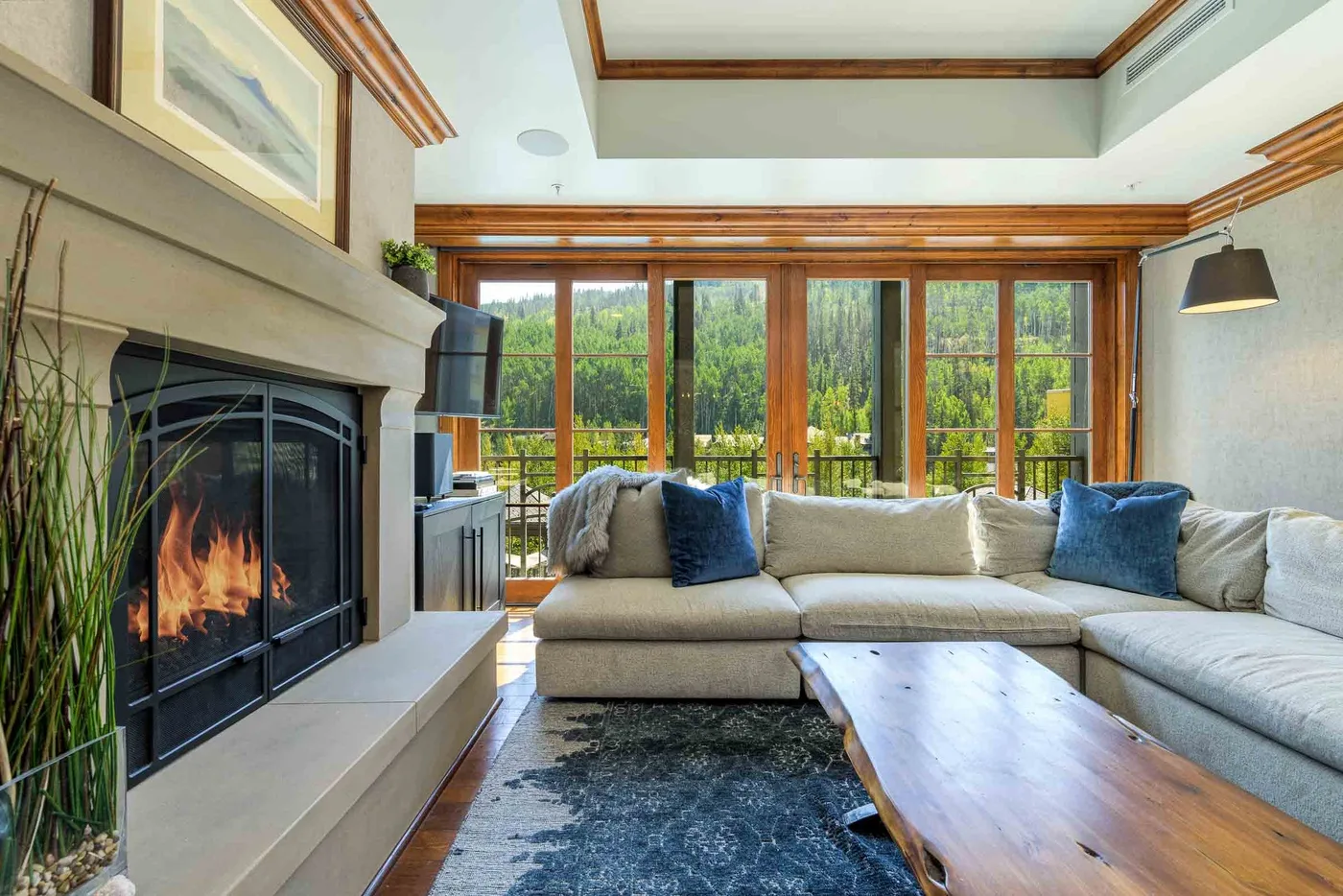 A bright living room with a fireplace, sectional seating, and large windows.