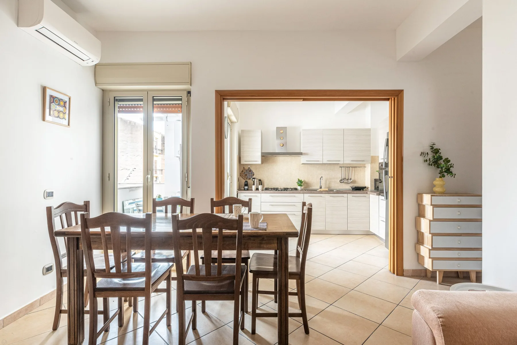 Un comedor con asientos de madera se abre a una cocina luminosa.