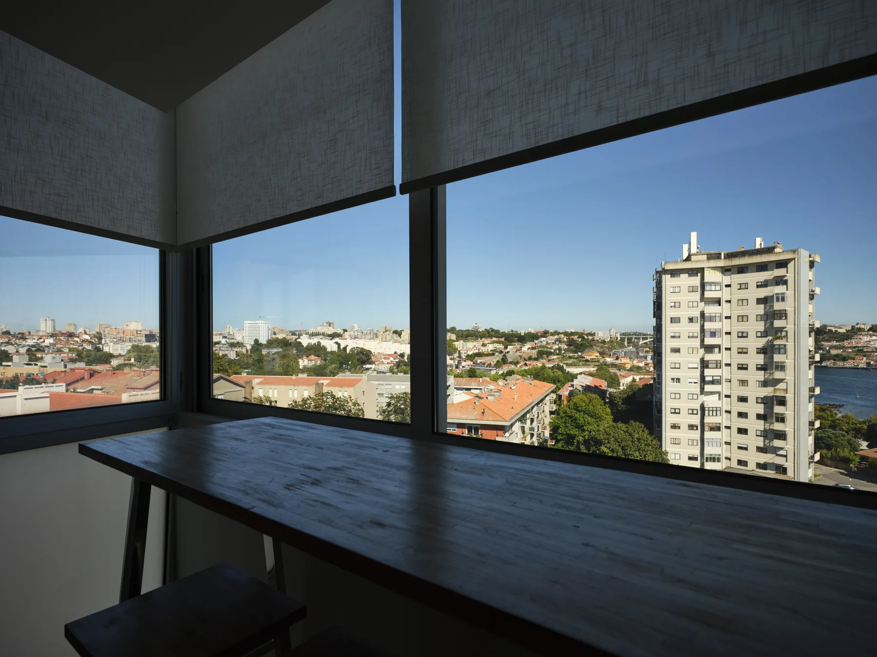 A dark counter sits beside wide windows overlooking a city neighborhood.