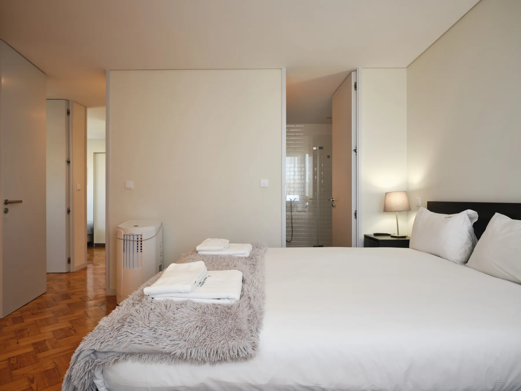 A bedroom with a neatly made bed and folded towels on a blanket.
