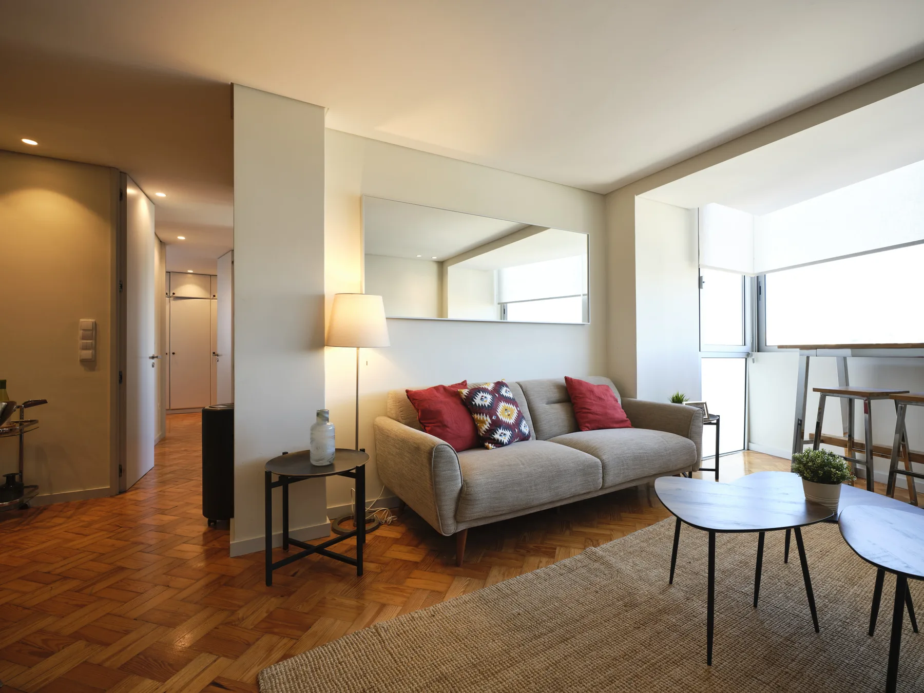 A bright living room with a sofa, coffee tables, and large windows.