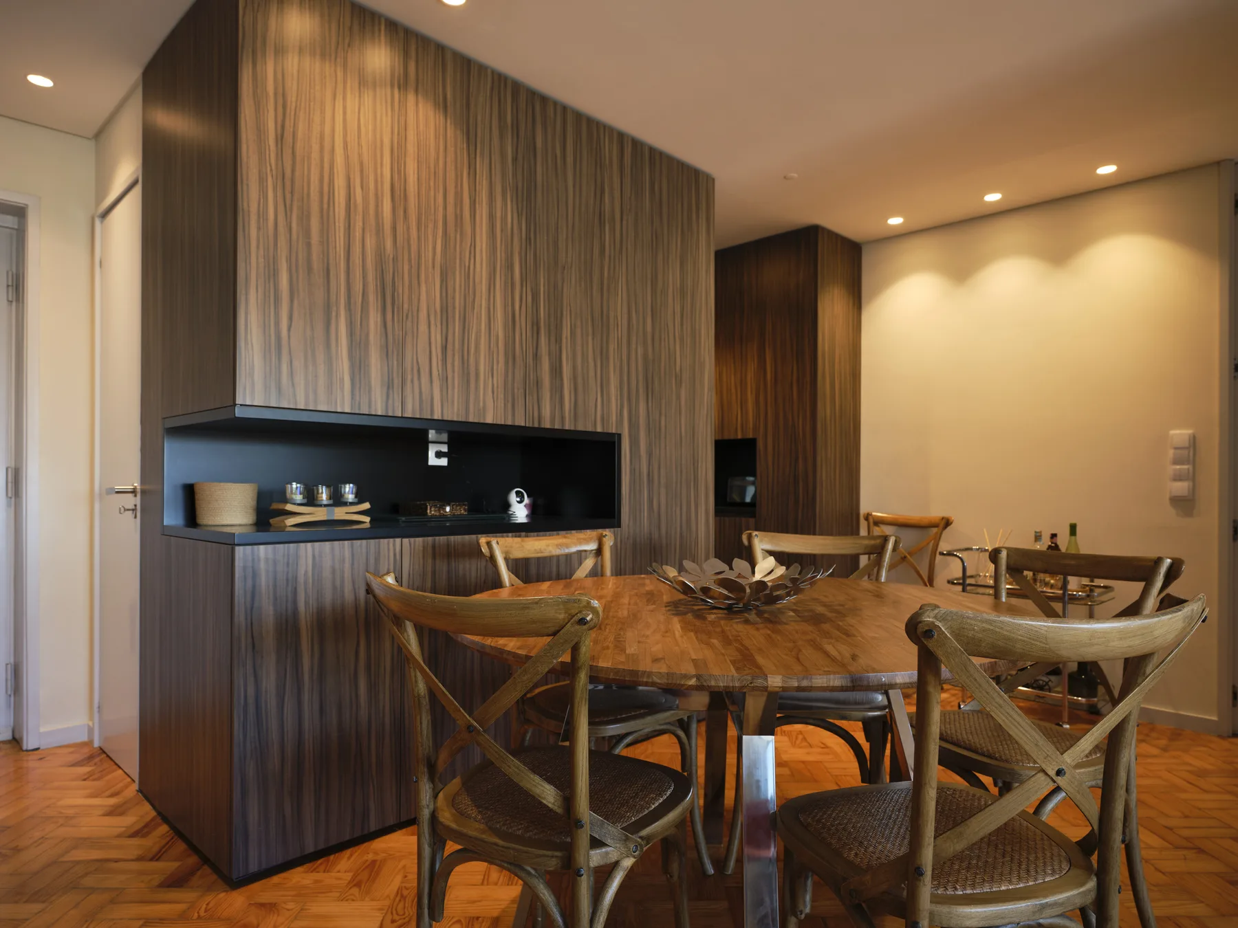 Dining area with a wooden table and chairs beside a built-in display shelf.