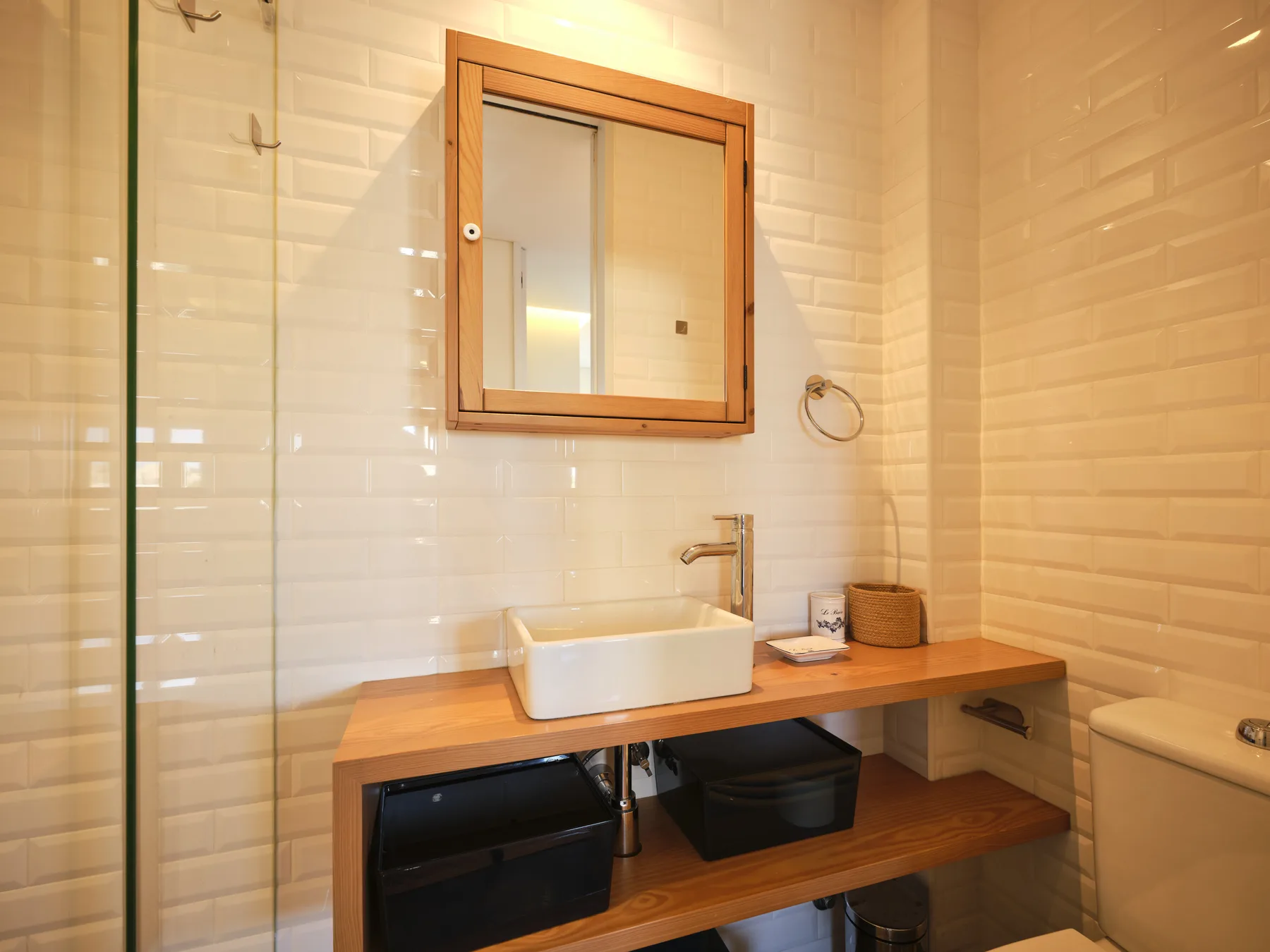 A tiled bathroom with a sink set into a wooden vanity.