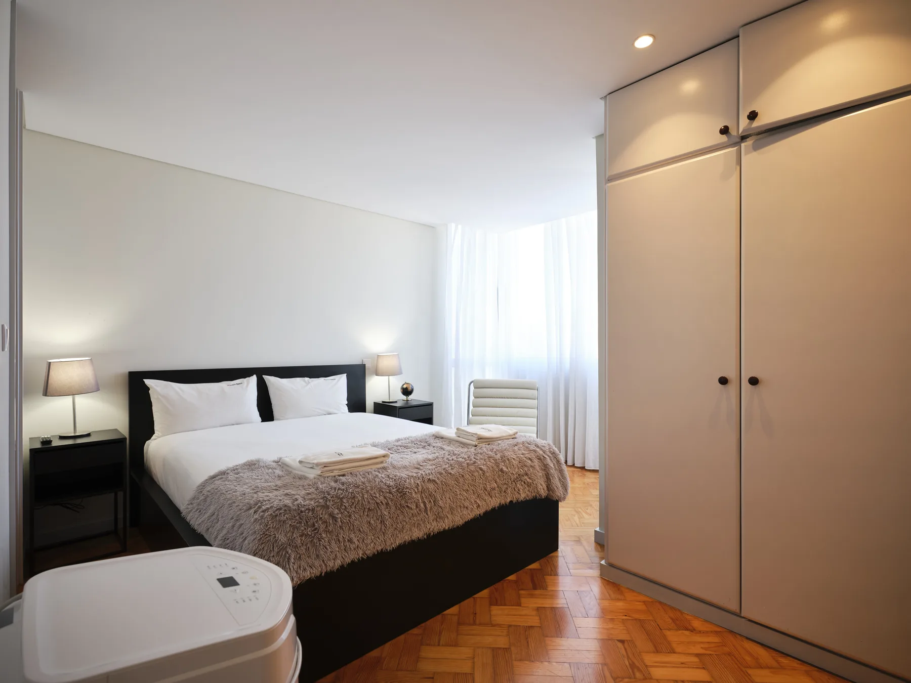 A bedroom with a bed, bedside tables, and a large wardrobe.