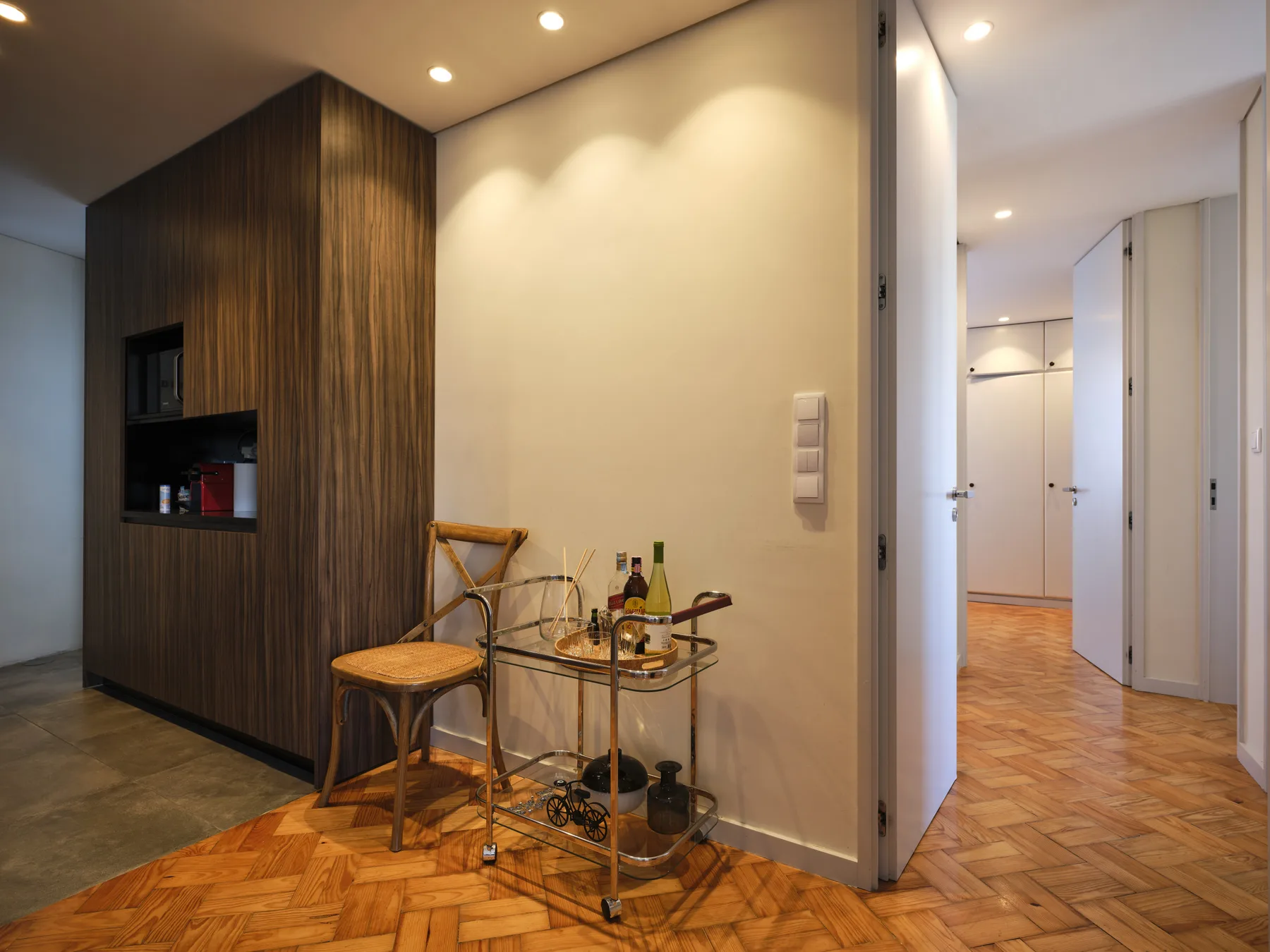 An apartment interior with a wooden cabinet, a small table, and a hallway.