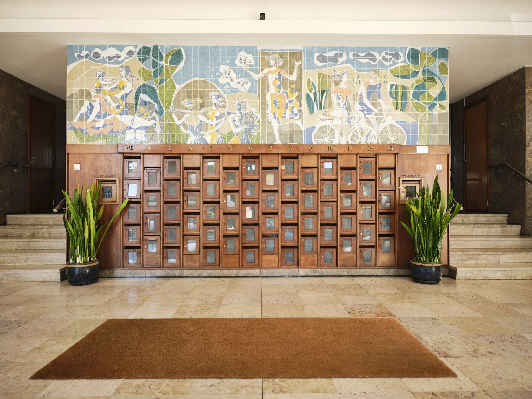 A lobby with a wooden mail cubby wall beneath a colorful mosaic.