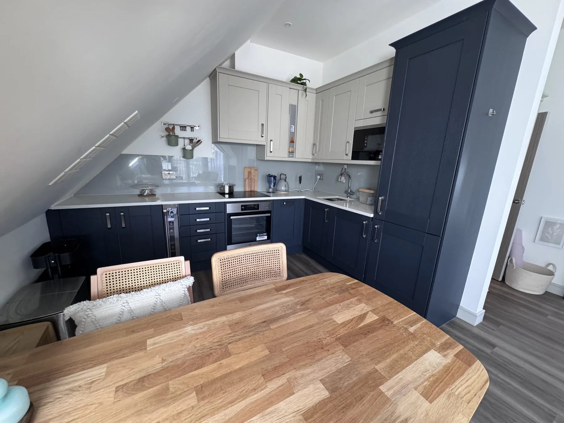 A compact kitchen with dark lower cabinets and a wooden dining table.