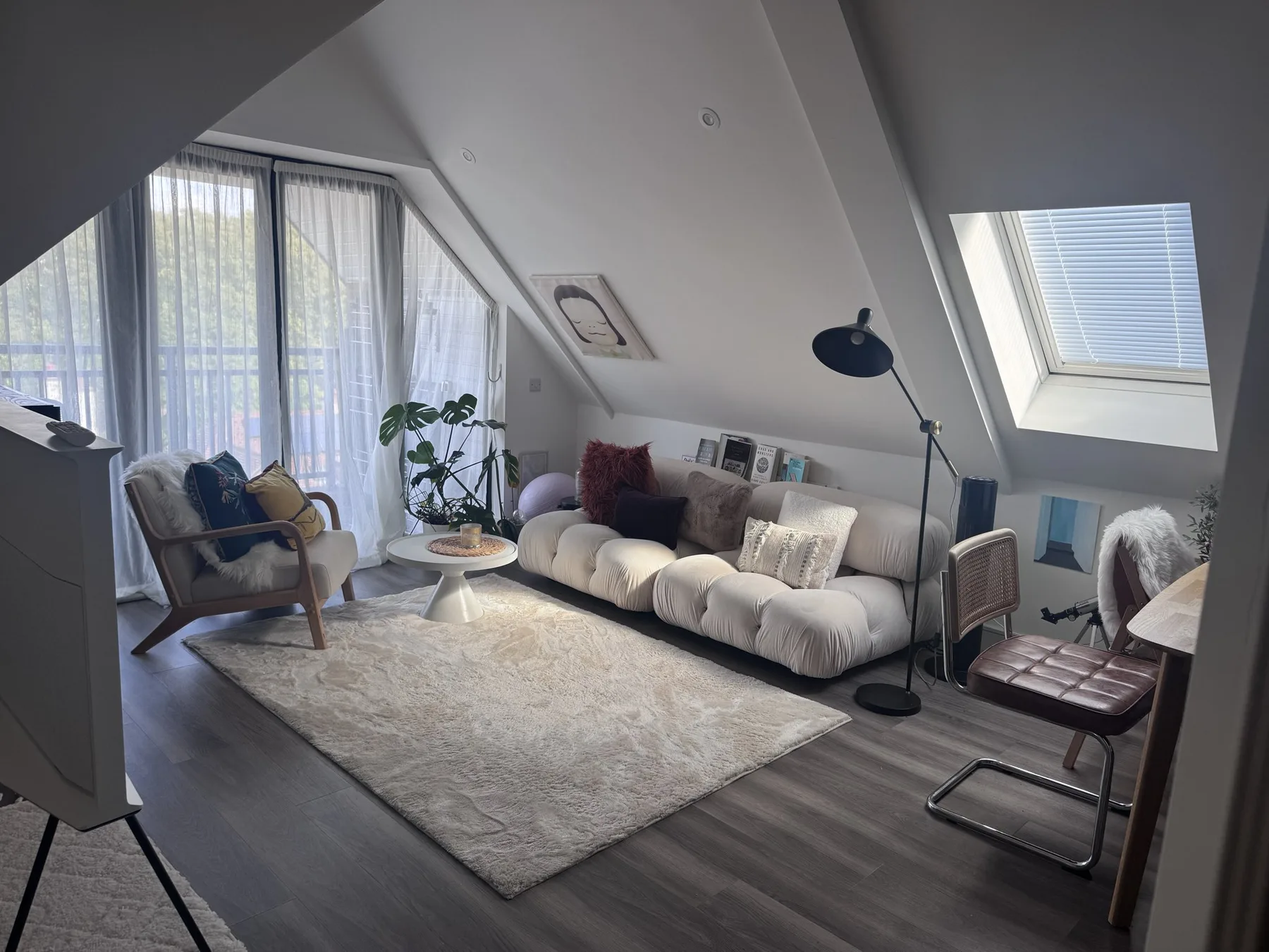 A bright attic living room with seating arranged around a large rug.