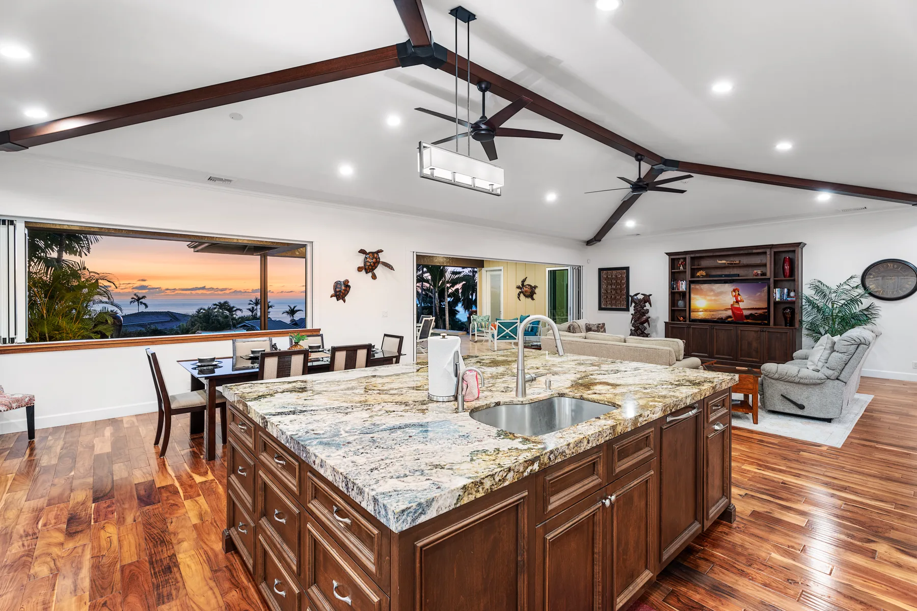 Una cocina y comedor abiertos cuentan con una isla grande y una mesa junto a las ventanas.