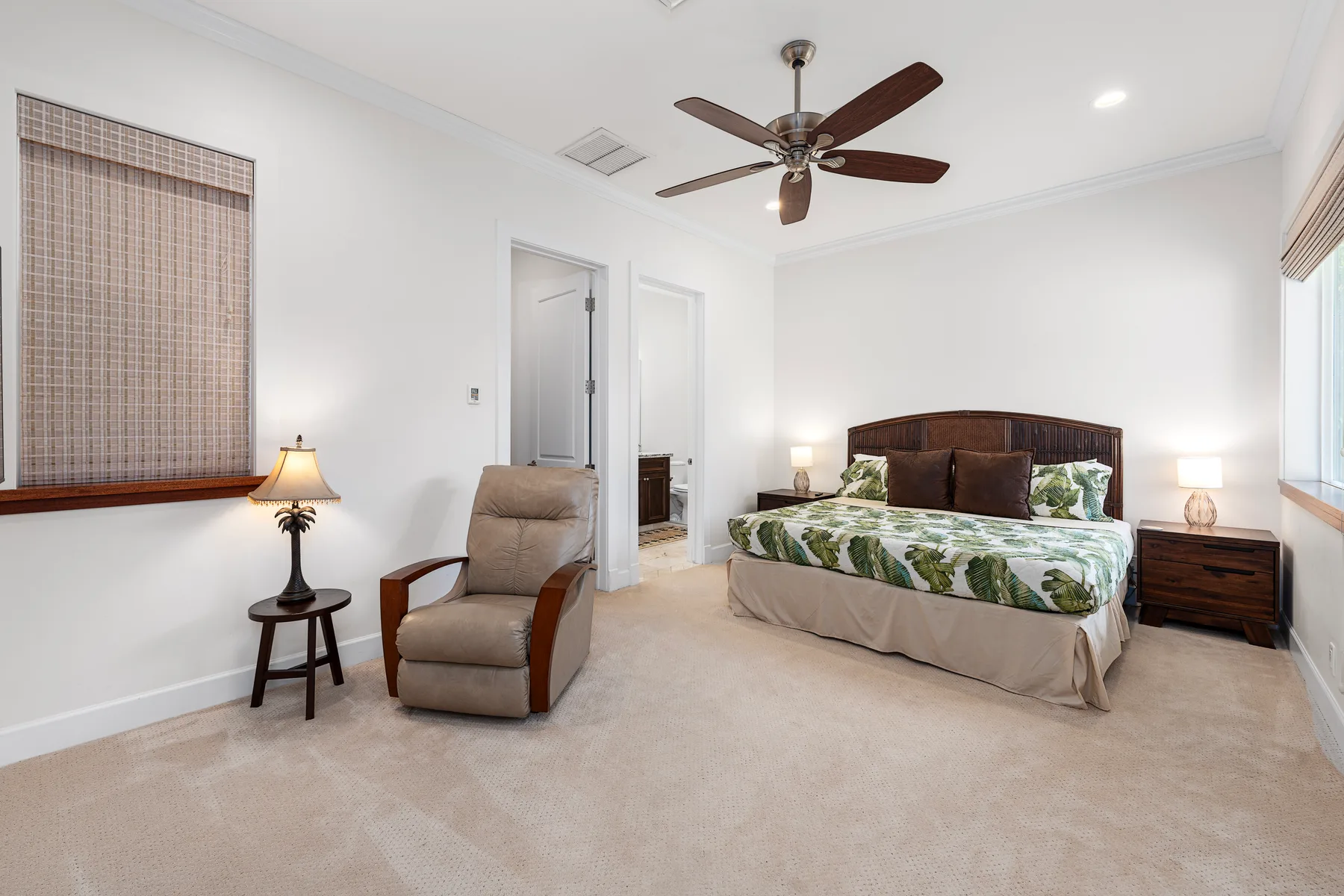 Dormitorio luminoso con una cama, un sillón y un ventilador de techo.