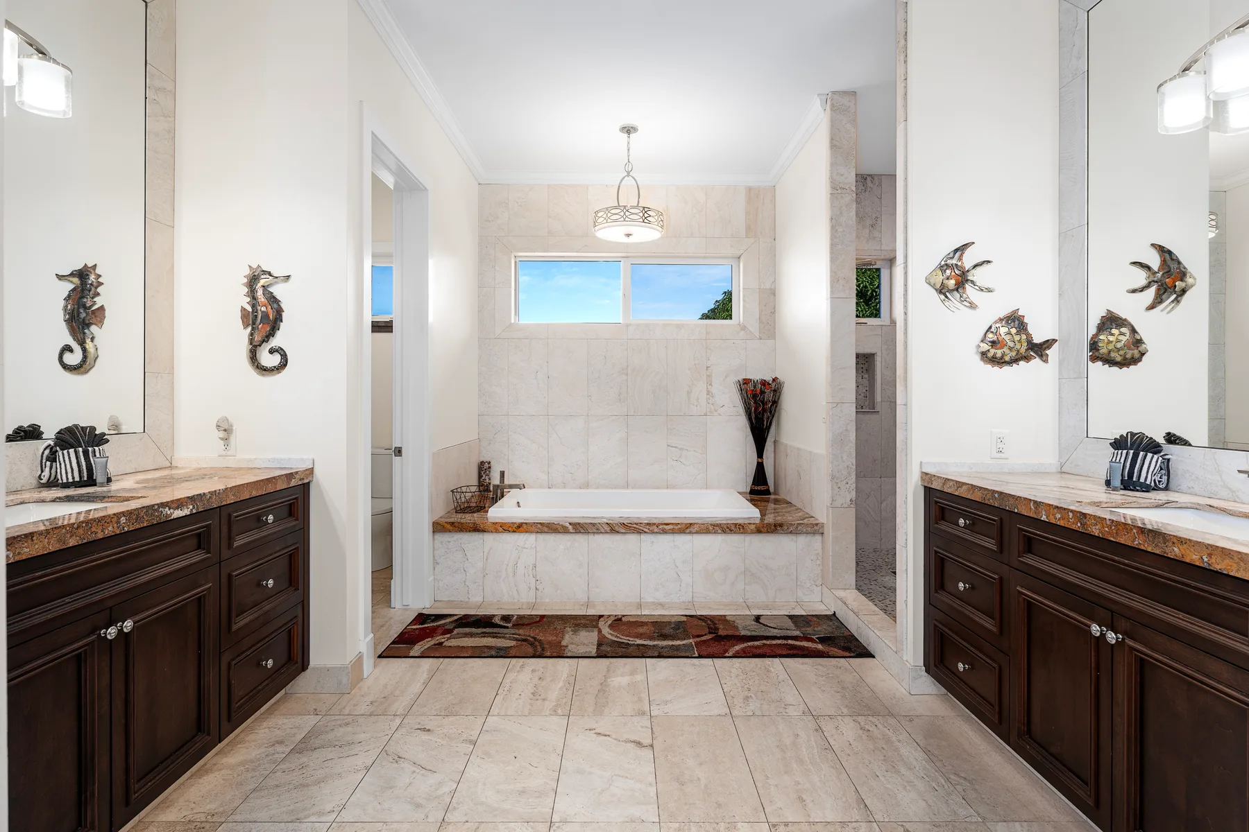 Un baño con una bañera grande entre dos tocadores de madera oscura.