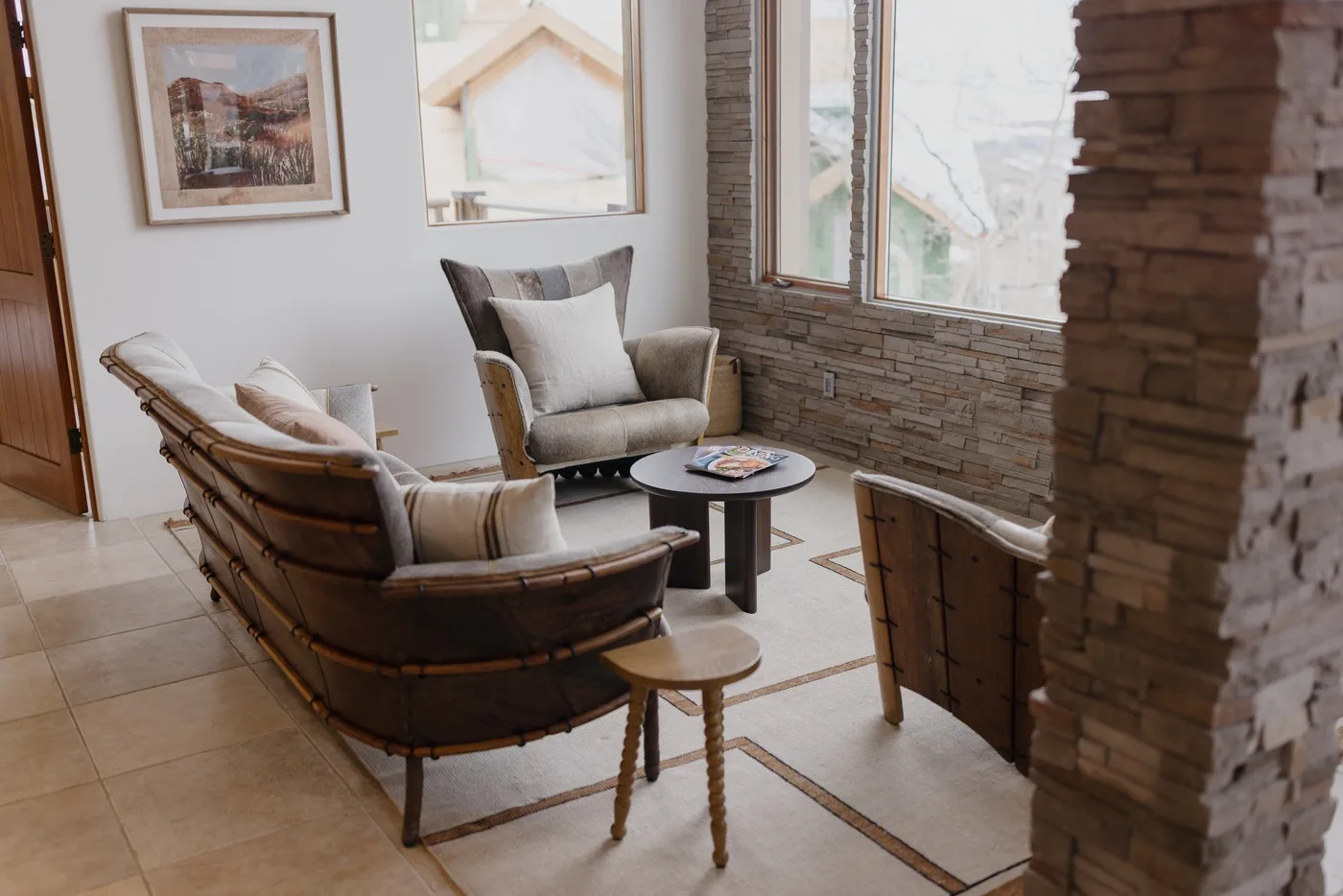 Una sala de estar con asientos acolchados y una mesa pequeña junto a grandes ventanas.