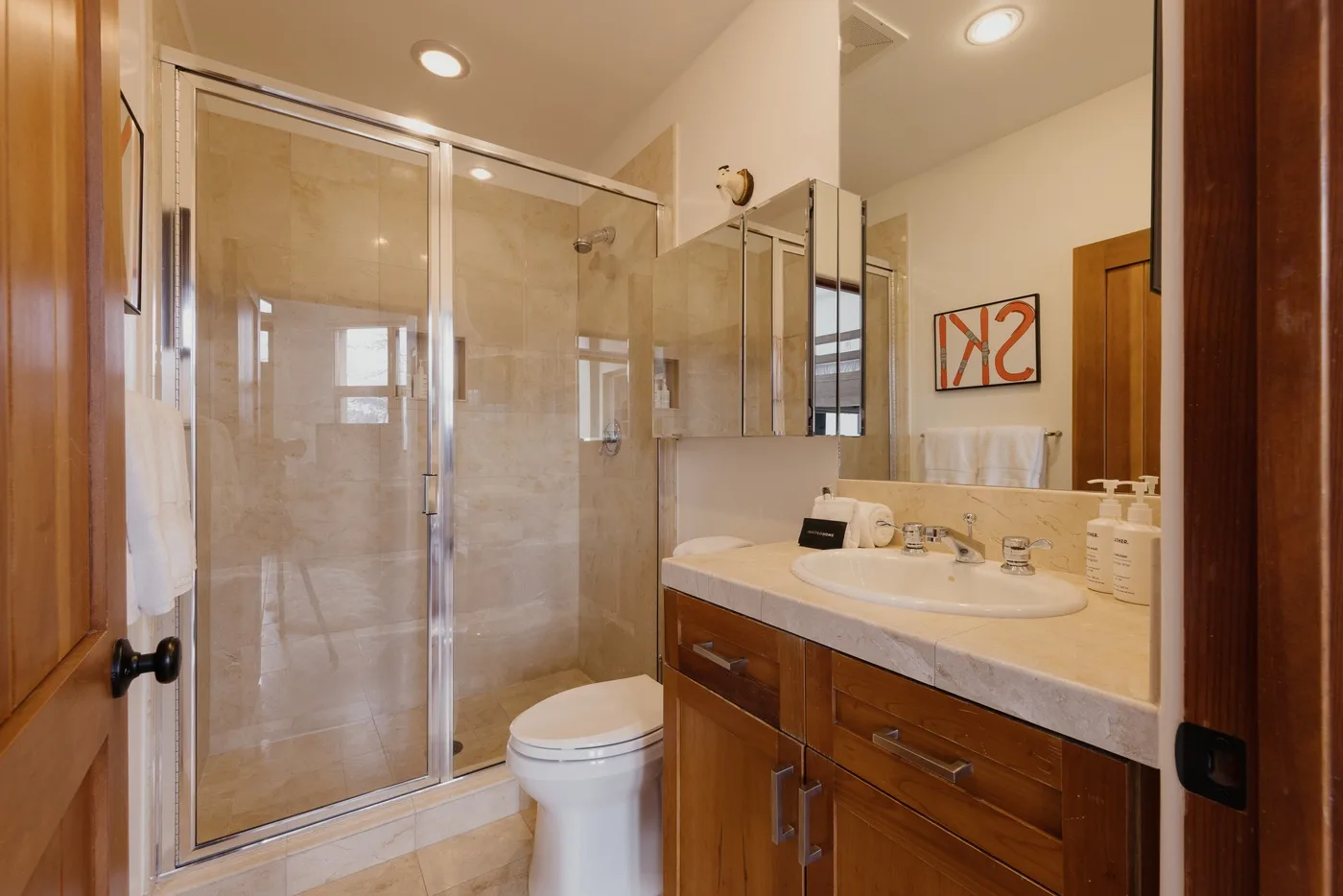 Un baño con ducha de cristal, inodoro y lavabo con mueble.