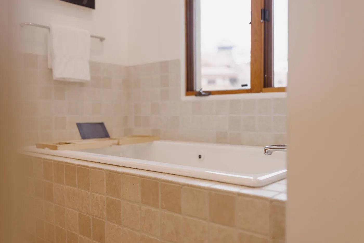Un baño alicatado con una bañera empotrada bajo una ventana.
