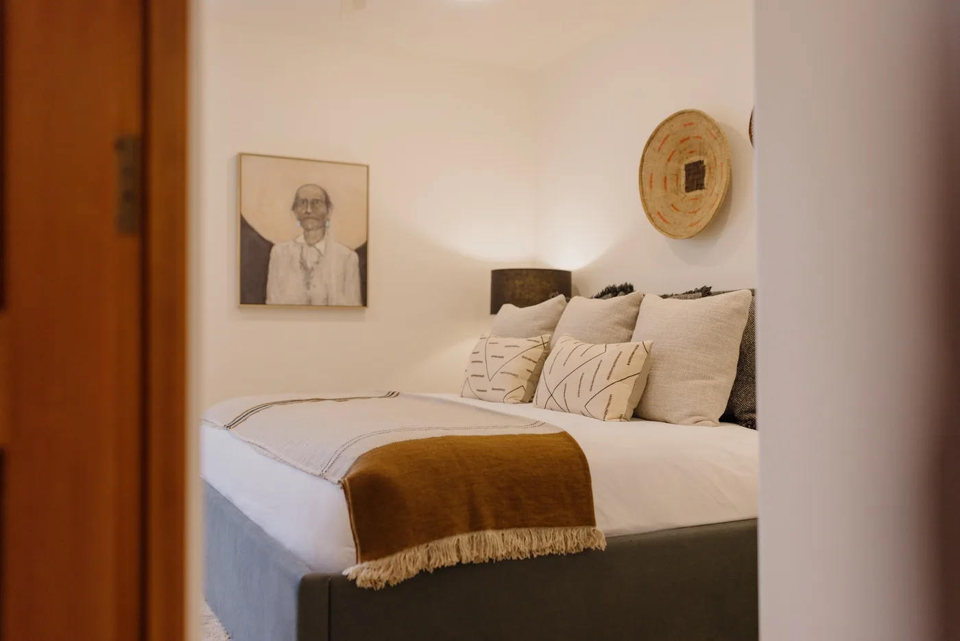 Un dormitorio con una cama bien hecha, almohadas y arte enmarcado en la pared.