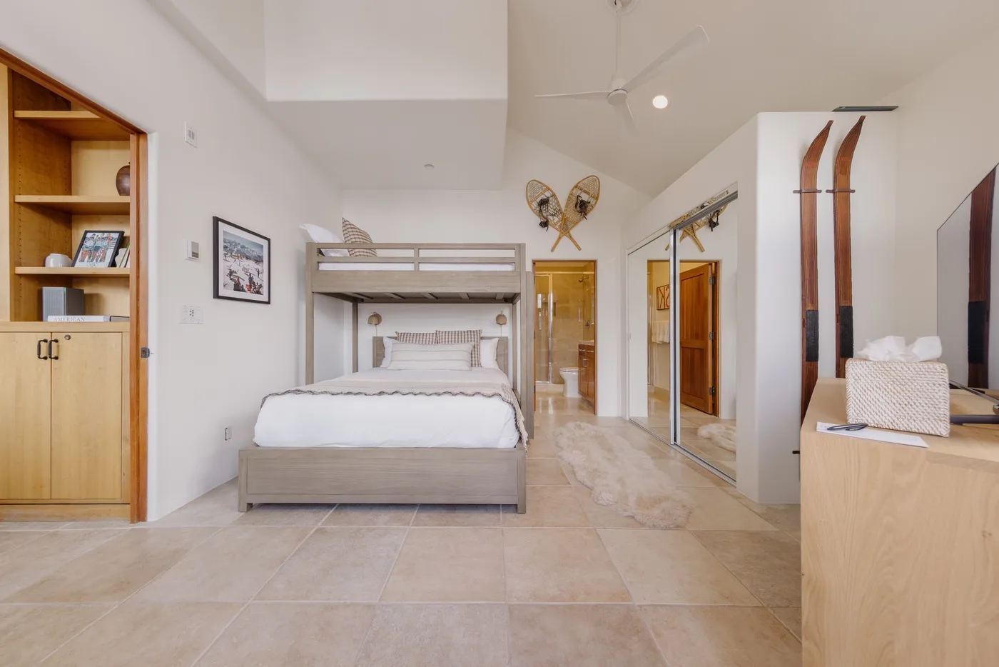 Un dormitorio luminoso con una zona elevada para dormir, una cama y suelo de baldosas.