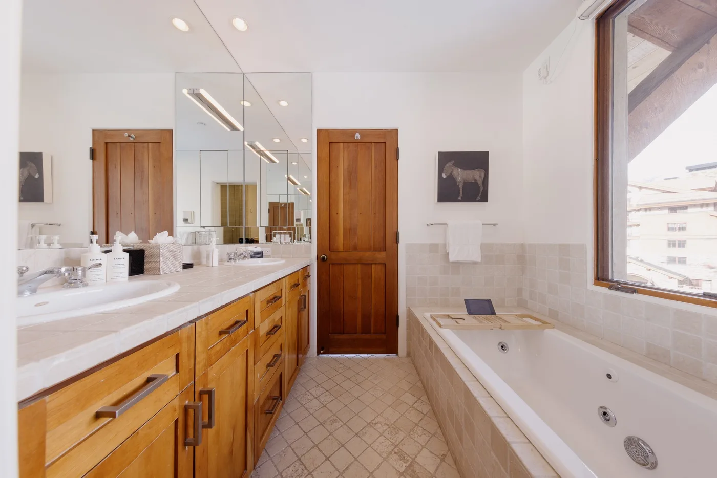 Un baño luminoso con un mueble de lavabo largo, pared con espejo y bañera.