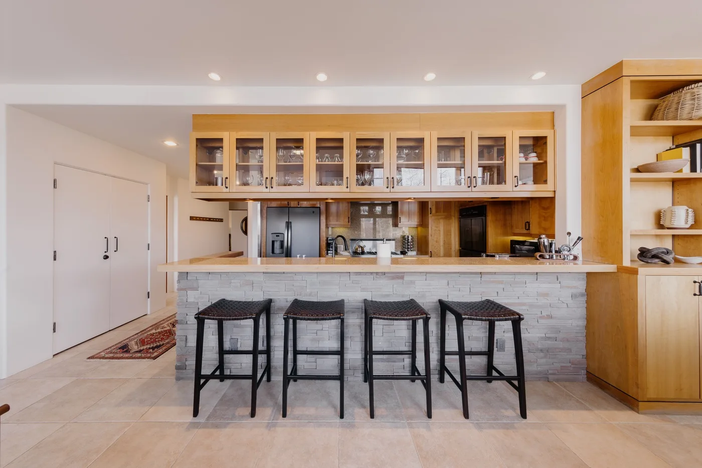 Una cocina con una barra larga, asientos y armarios de madera.