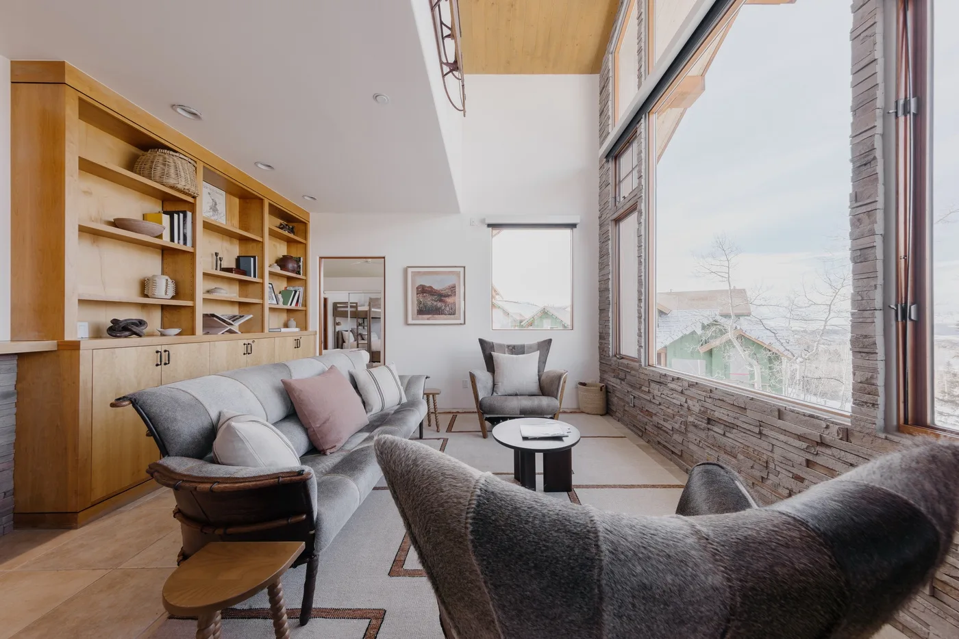 A bright living room with seating beside large windows and built-in shelves.