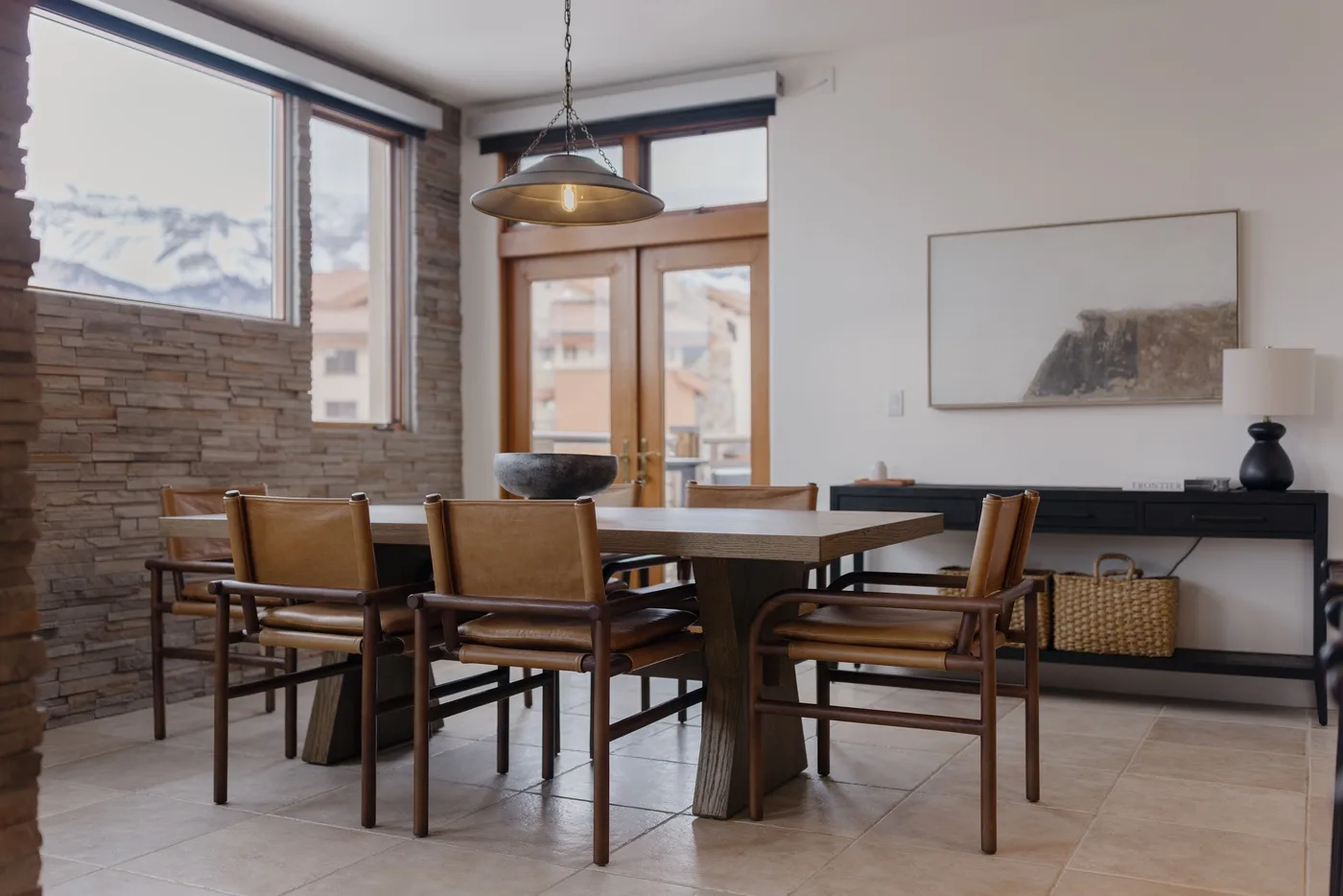 Comedor con una mesa de madera y sillas junto a grandes ventanas.