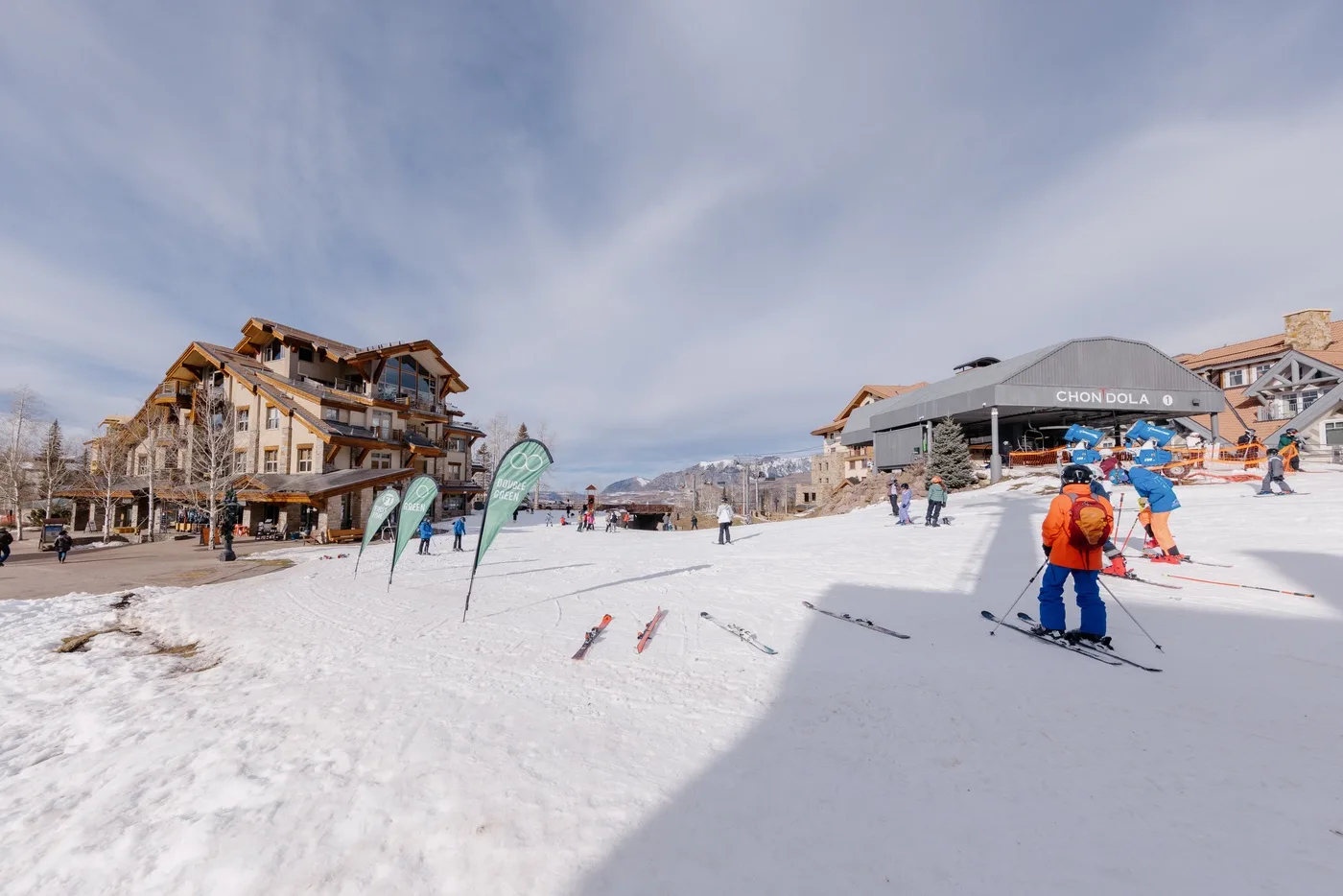 Una zona de esquí nevada con esquiadores cerca de un alojamiento y una estación de remontes.