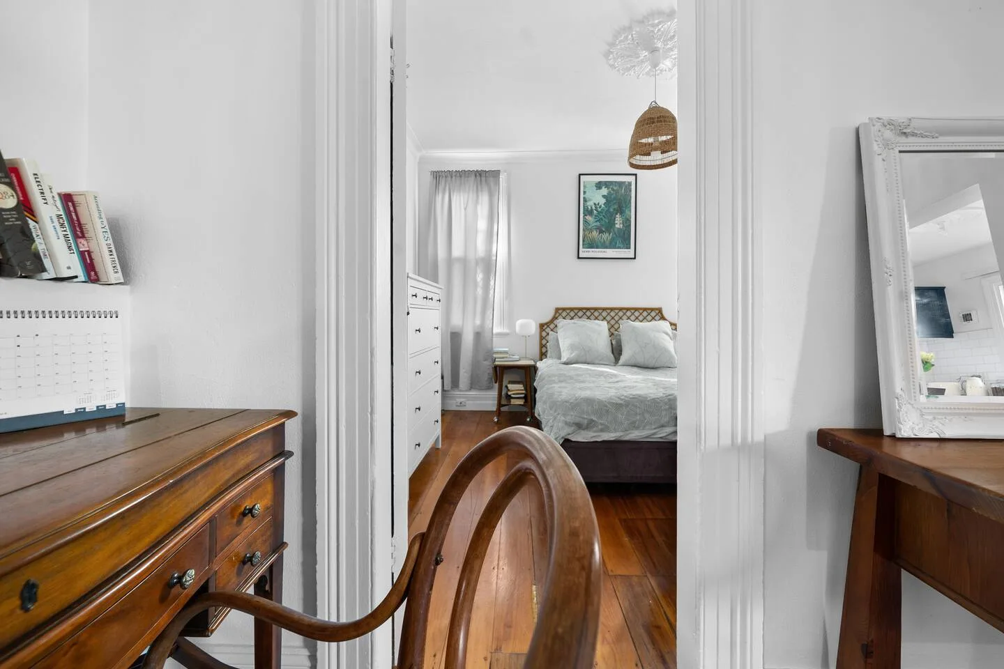 Se ve un dormitorio con una cama y mesitas de noche a través de la puerta.