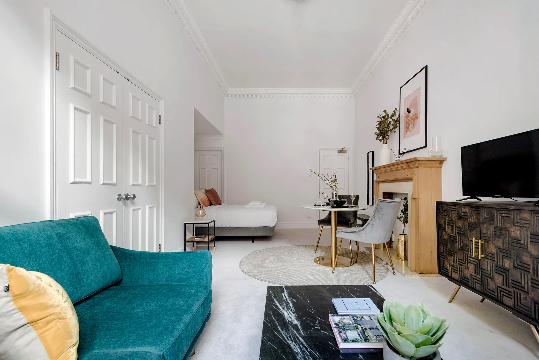 A bright living room with teal seating and a dining table.