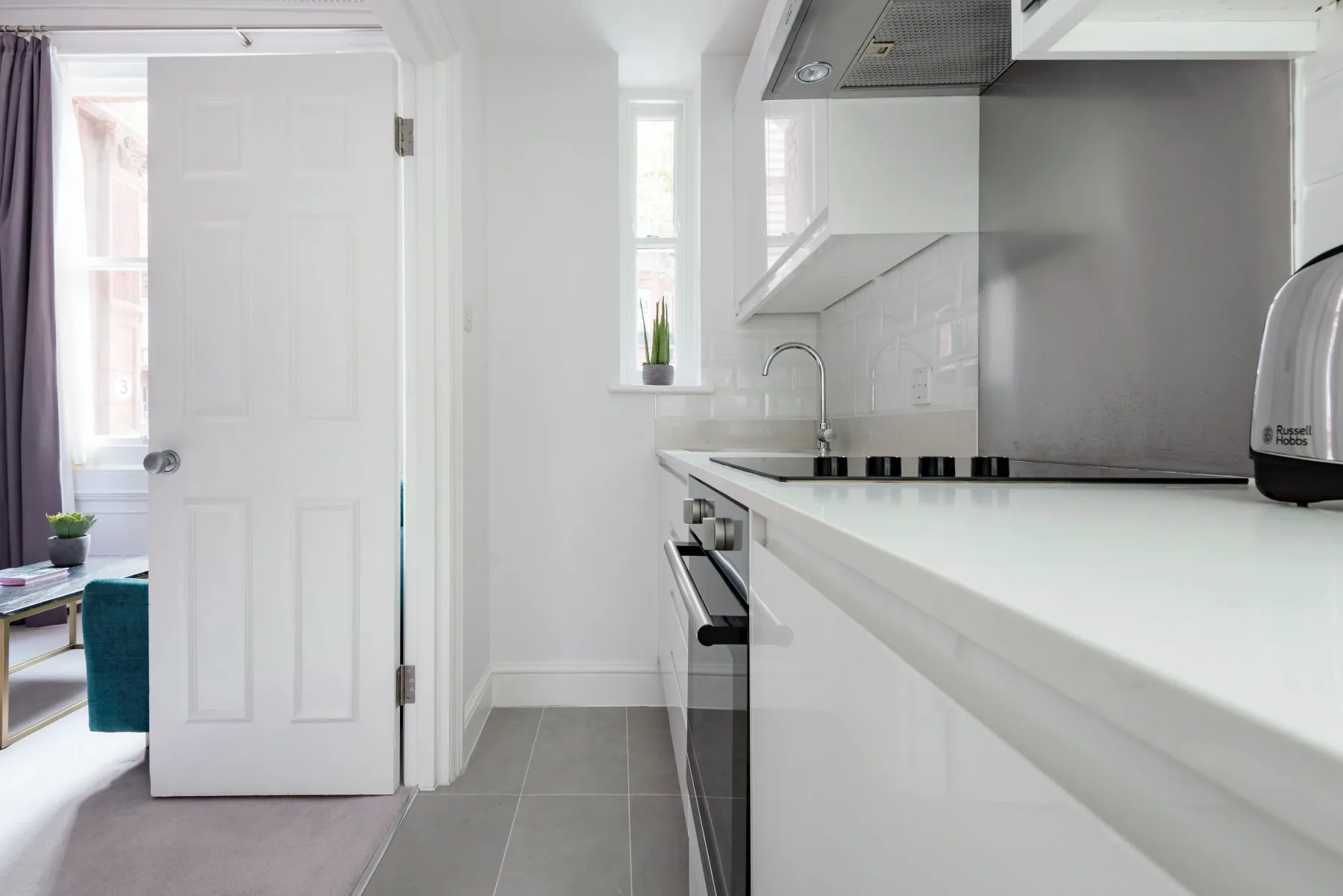 A bright kitchen with white cabinets and a long countertop.