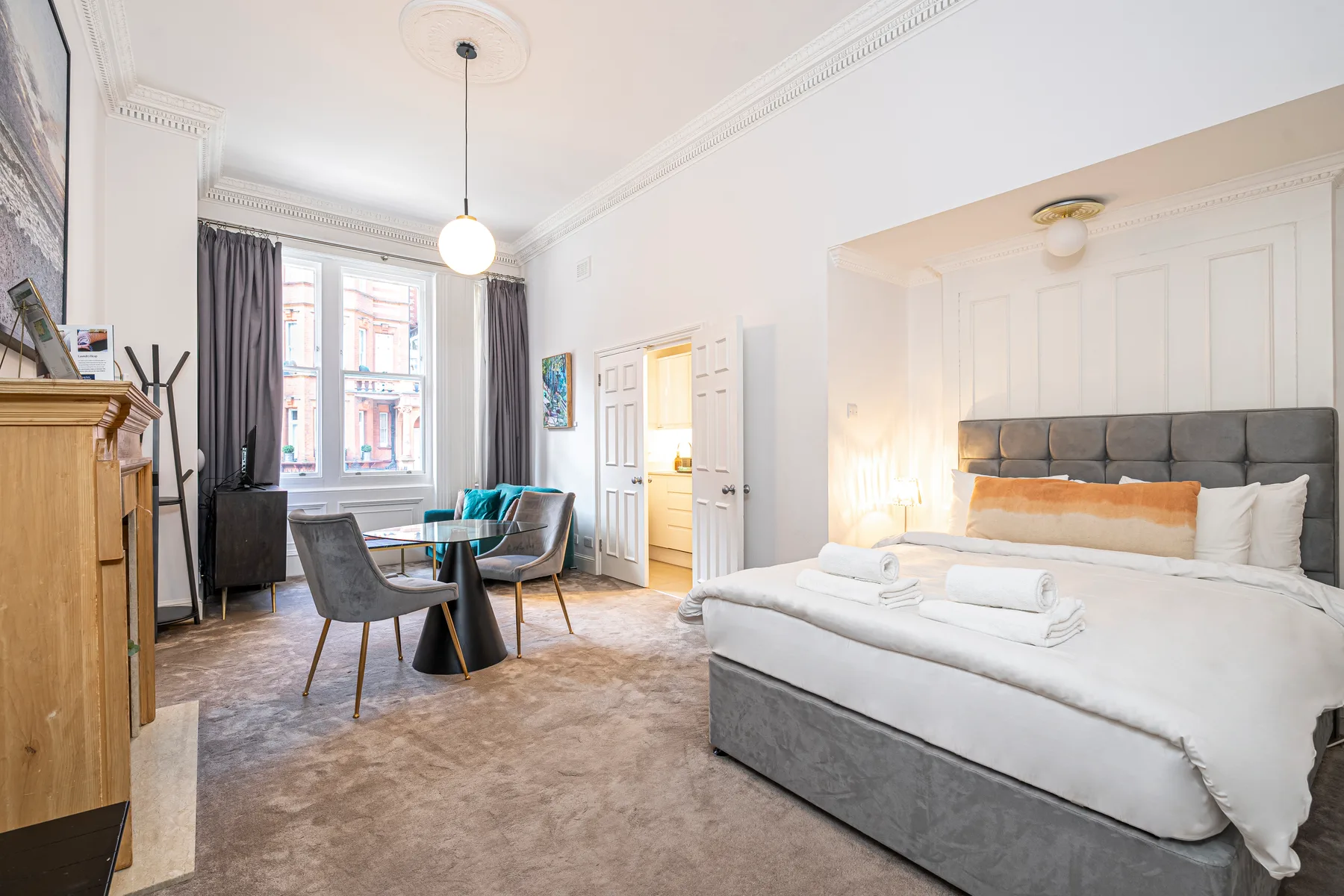 A bright bedroom with a large bed and a small seating area by the window.