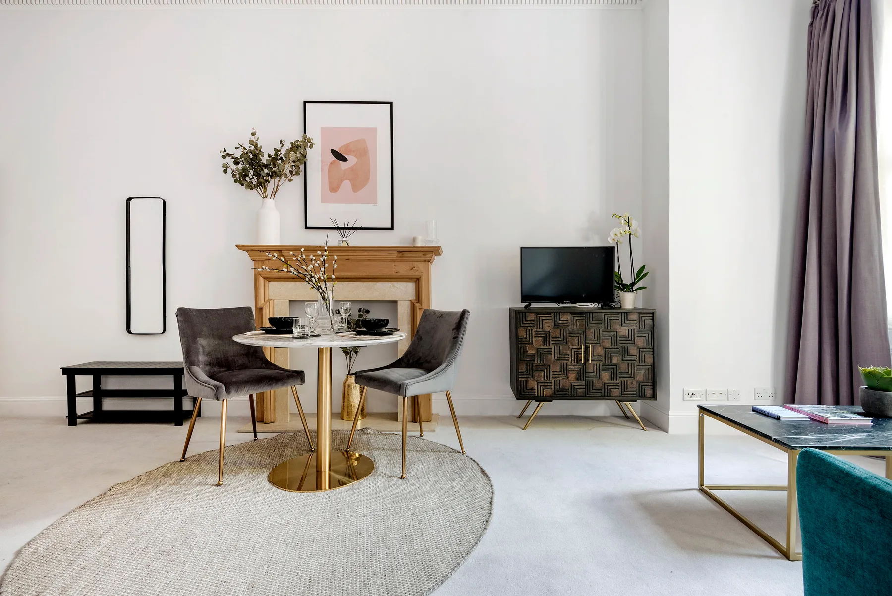 A bright living and dining area with a round table, seating, and a fireplace.