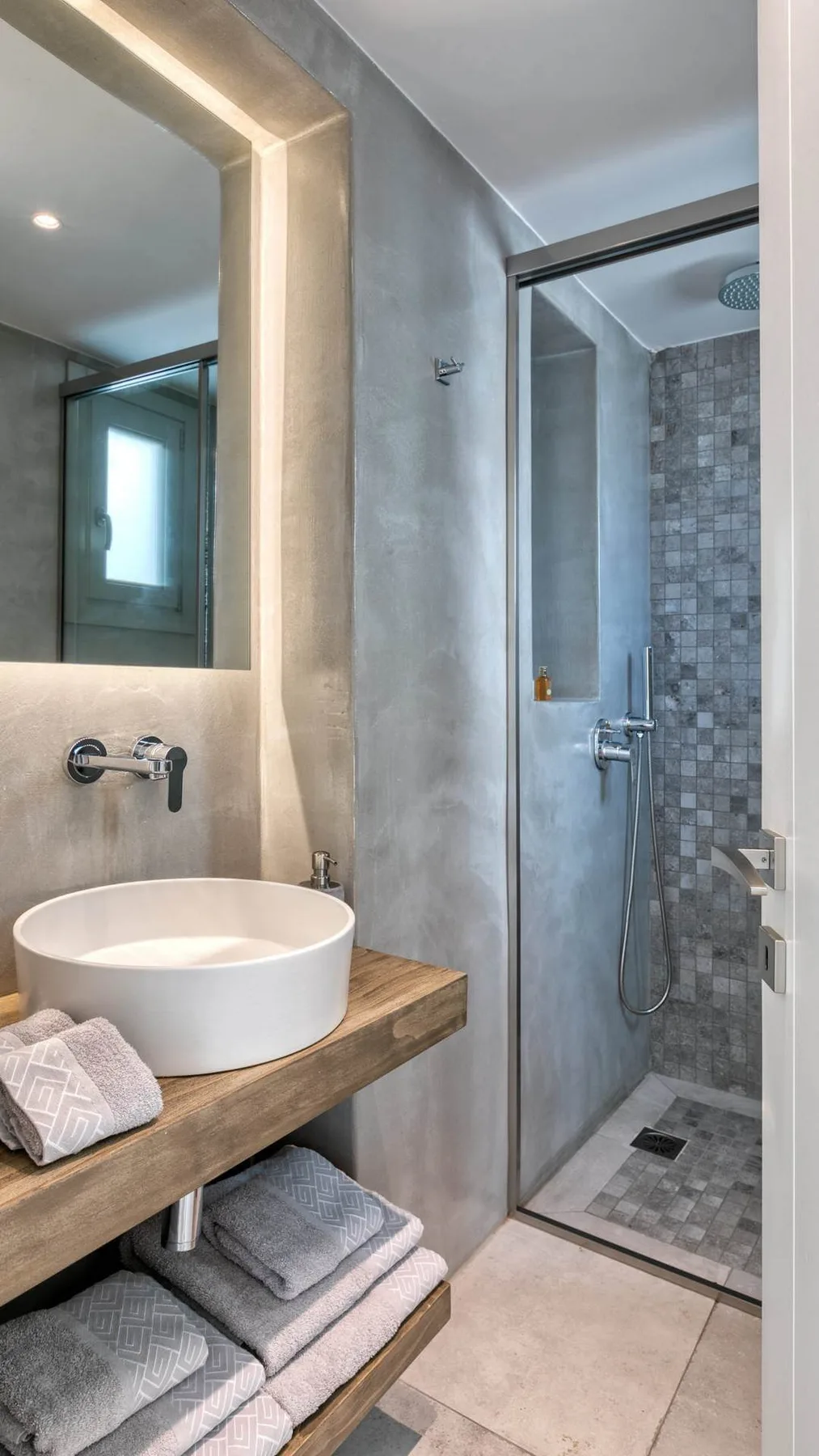A bathroom vanity with a vessel sink sits beside a glass shower.