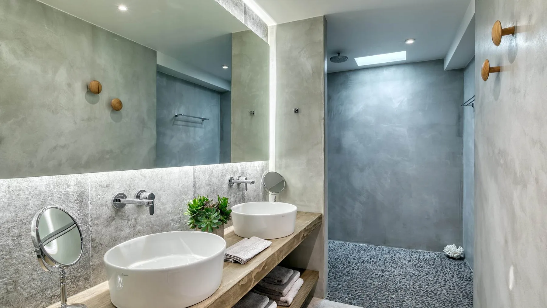A modern bathroom with a long vanity and a walk-in shower.