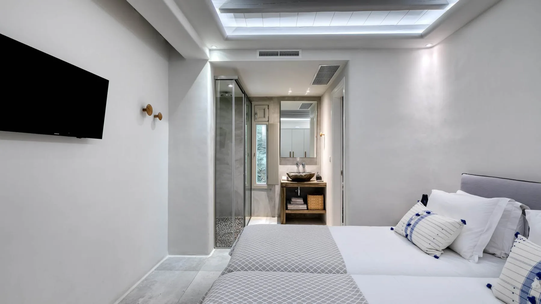 A bedroom with a bed, wall-mounted television, and an adjoining bathroom.