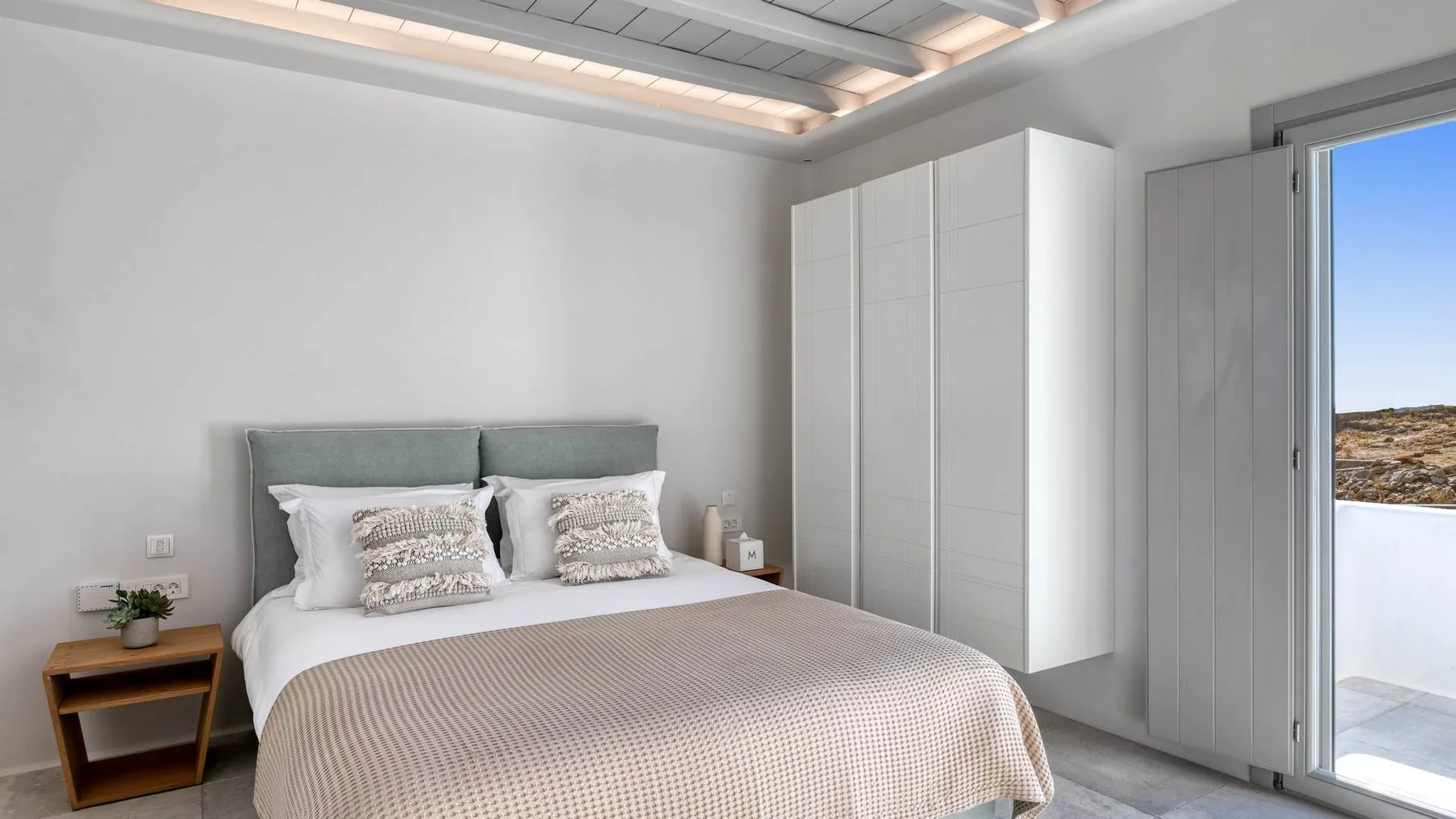 A bedroom with a double bed and white wardrobes.