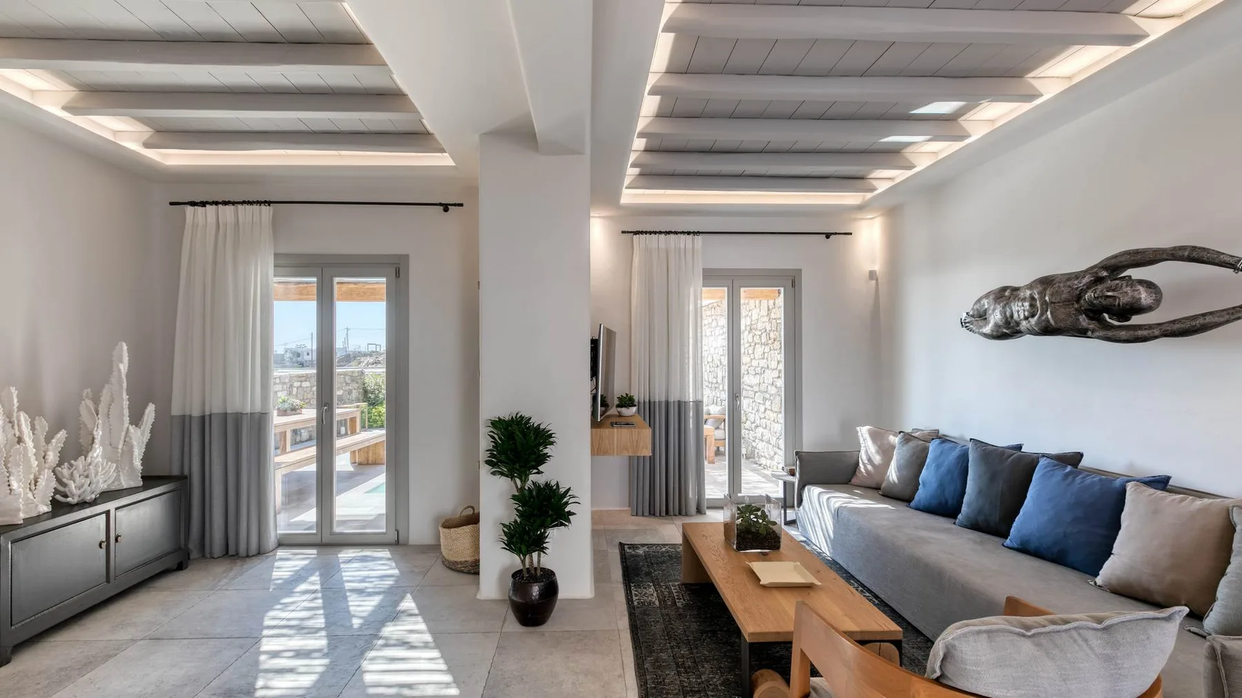 A bright living room with seating, a coffee table, and large windows.