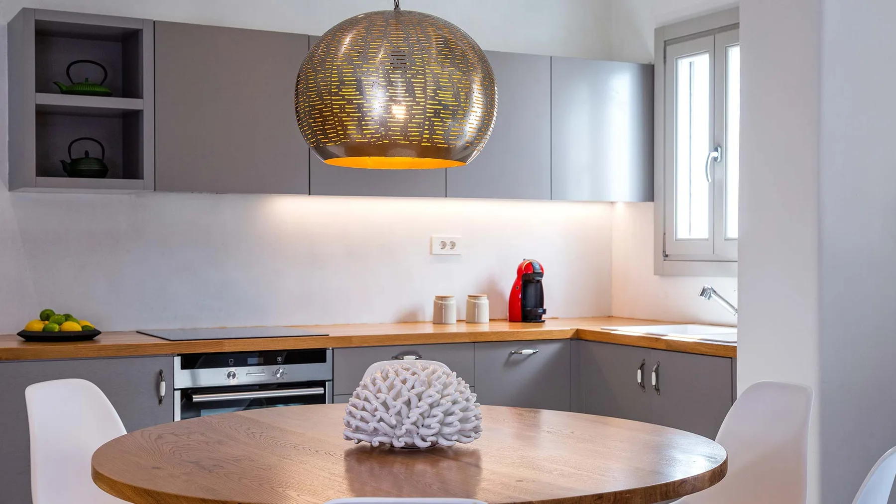 A modern kitchen with gray cabinets and a round dining table.