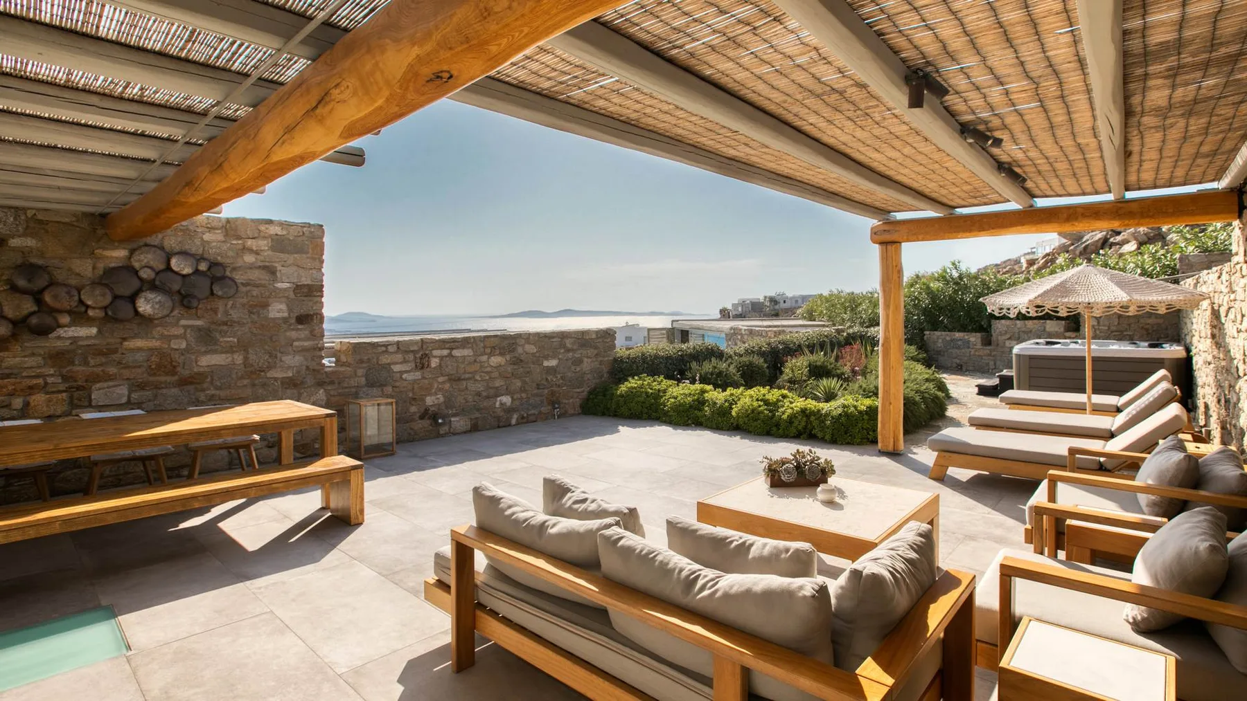 A shaded outdoor lounge with wooden seating and a stone terrace wall.