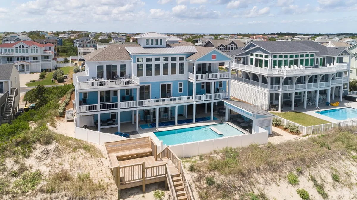 A large beachfront house with blue balconies and a swimming pool.