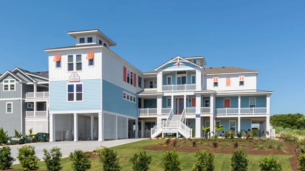 A large elevated coastal-style house with balconies and white exterior stairs.