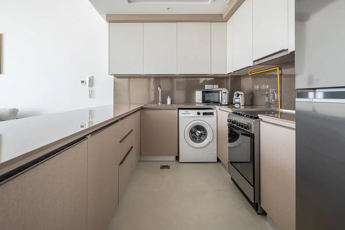 A modern kitchen with a washing machine, oven, and countertop appliances.