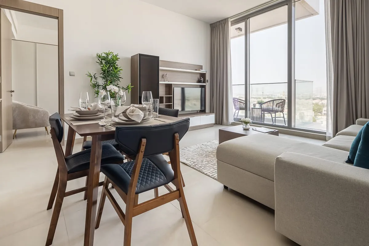 A bright living and dining area opens onto a balcony through large glass doors.