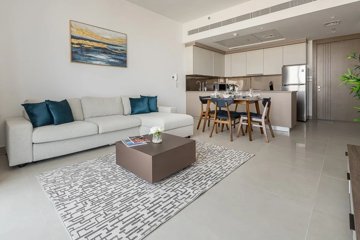 A living and dining area with light seating and a table beside the kitchen.